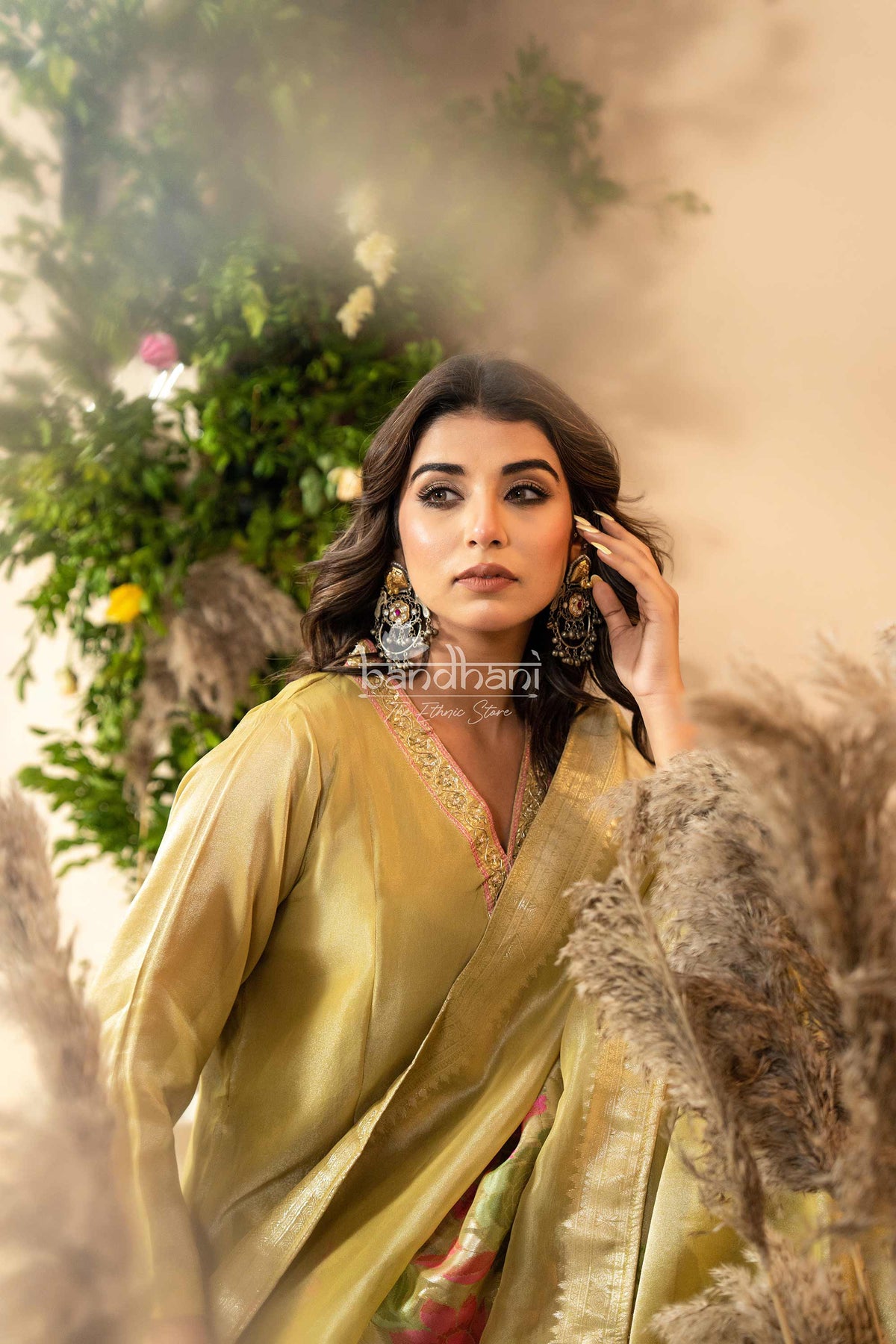 Woman in a green saree with floral kurti pant dupatta set  and 'bandhani' branding.