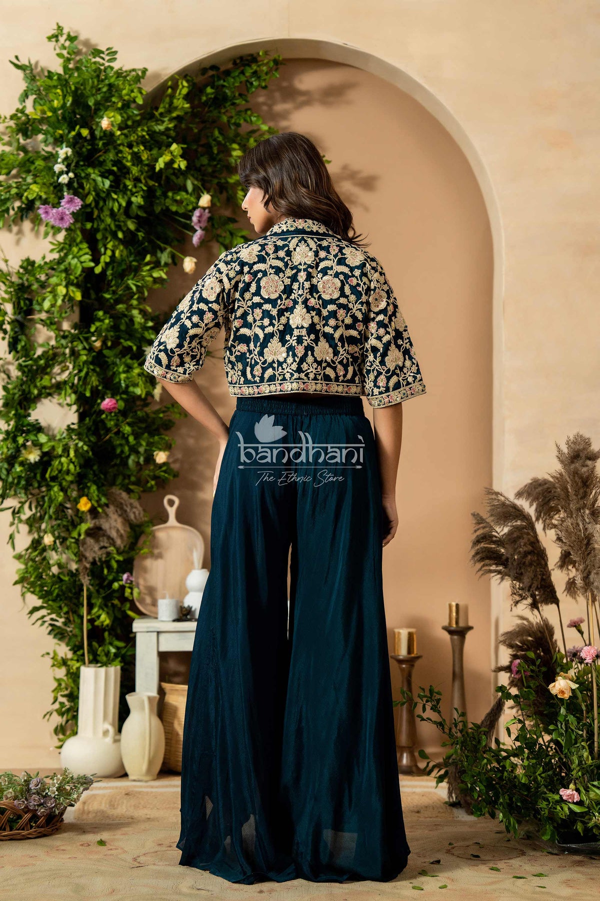 Person wearing a traditional outfit with floral patterns in a decorative setting.