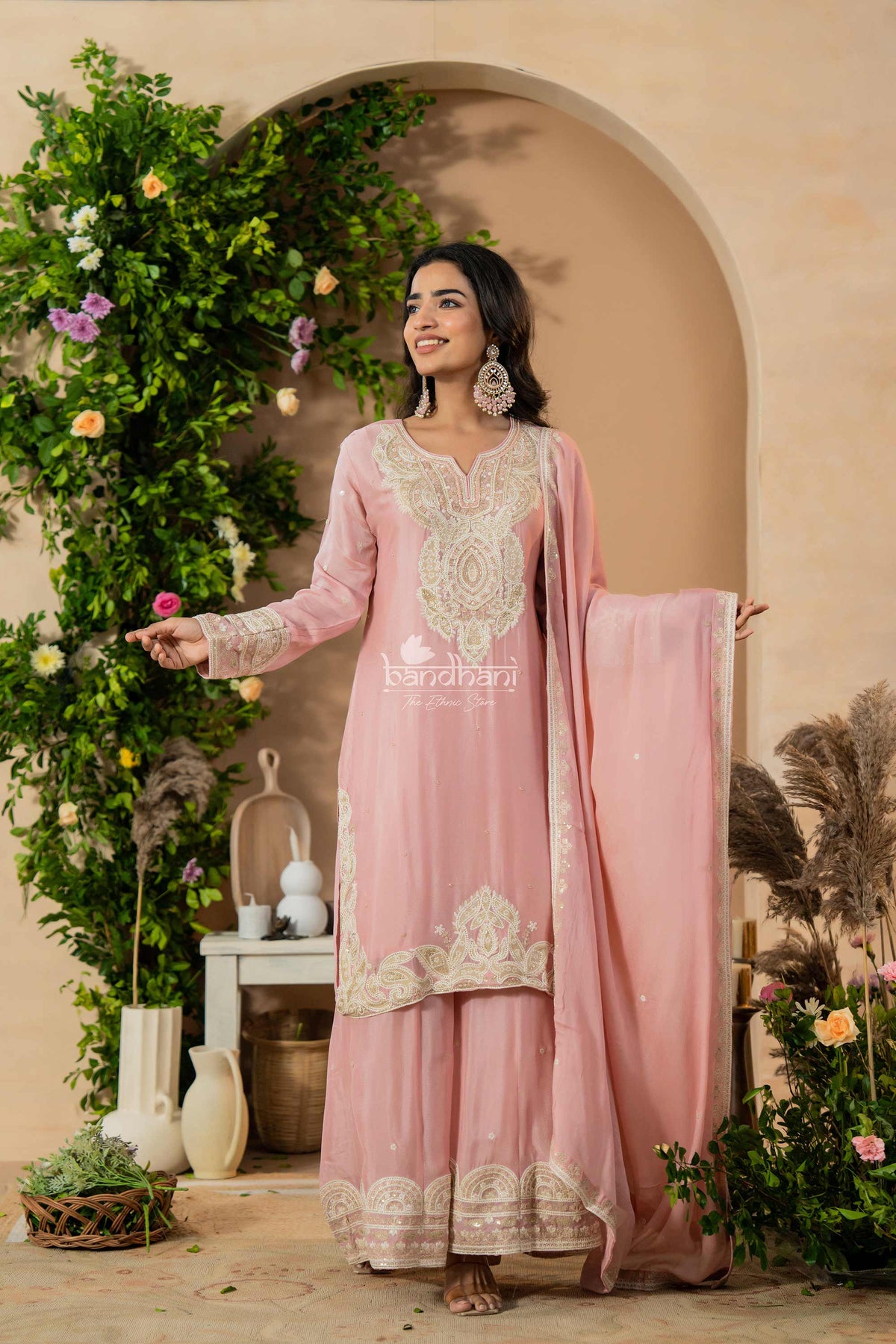 Woman in a pink traditional outfit with floral decorations and greenery.