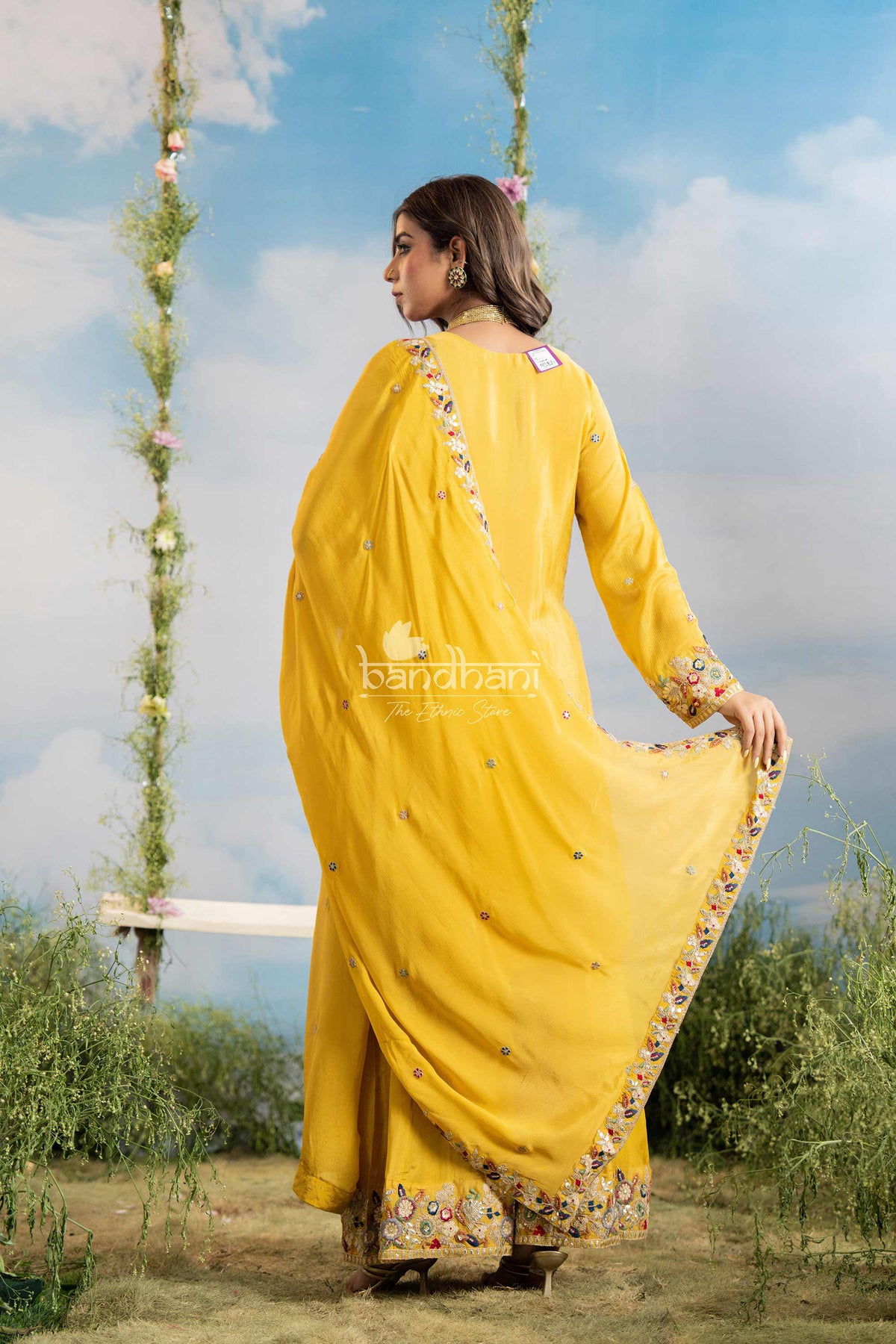 Woman in a yellow saree with floral decorations against a natural background