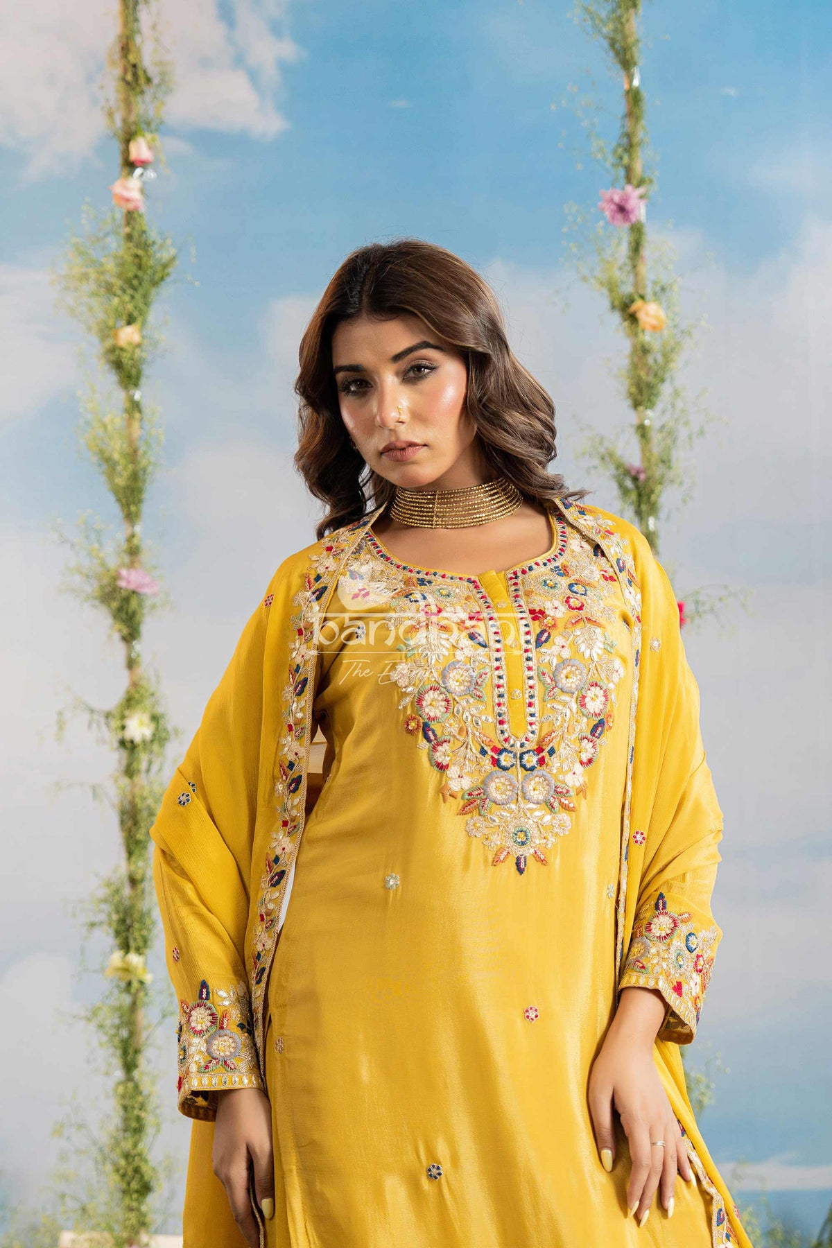 Woman wearing a yellow embroidered outfit with a scenic background