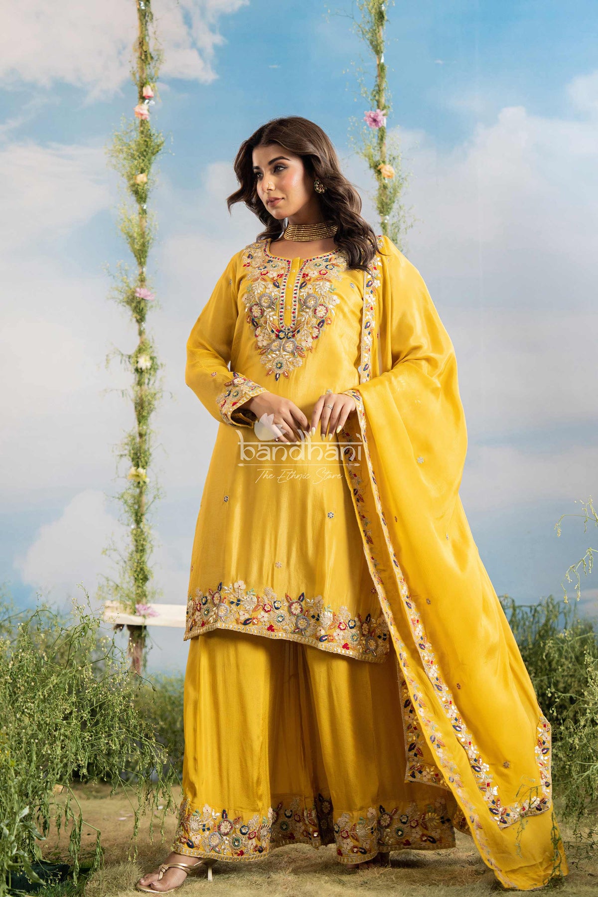 Woman in a yellow traditional outfit with floral embroidery against a natural background