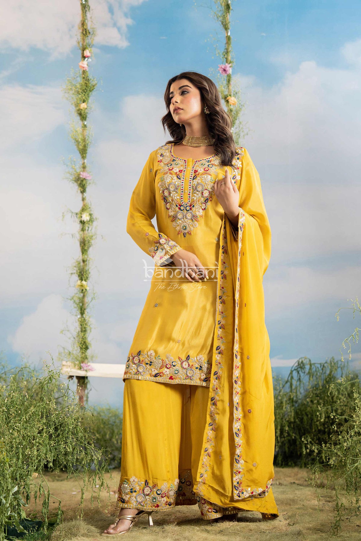 Woman in a yellow traditional outfit with floral patterns against a scenic background