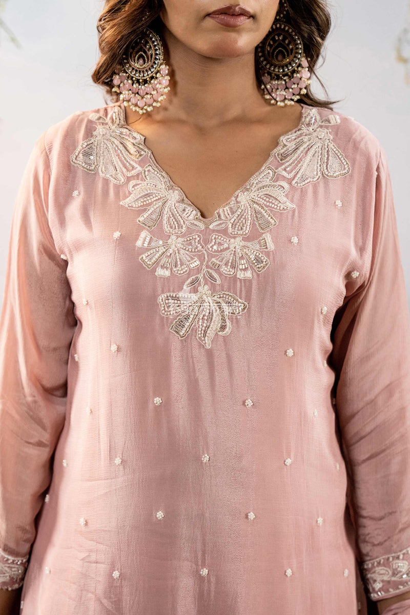 Pink embroidered dress with intricate detailing on a plain background