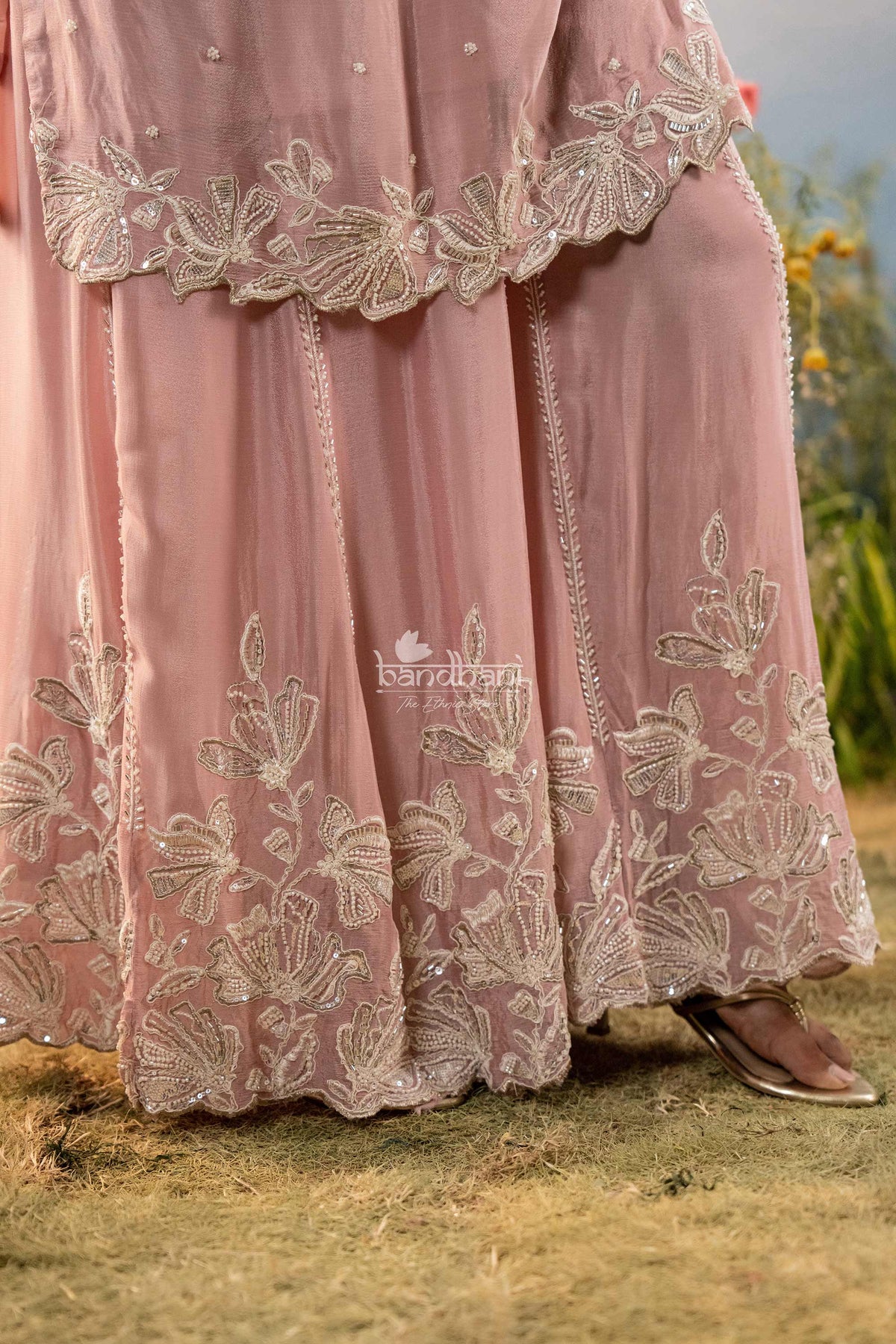 Pink traditional outfit with intricate white embroidery on a natural background