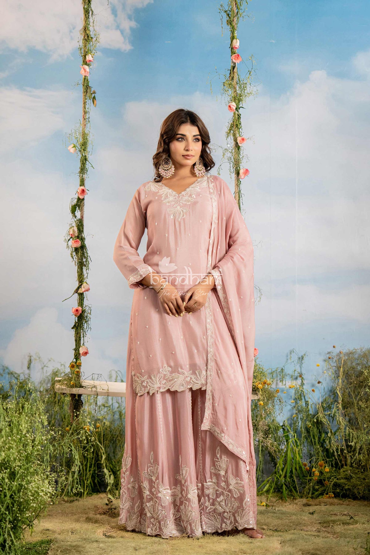 Woman in a pink traditional outfit sitting on a swing with a scenic background