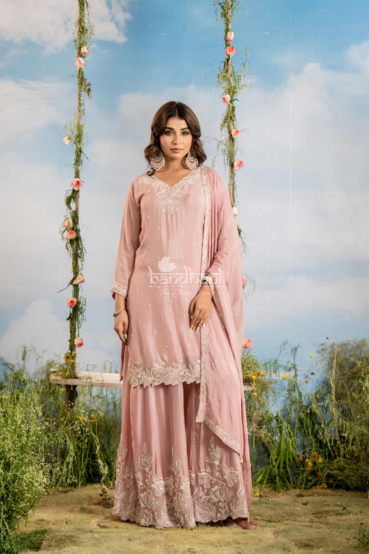 Woman in a pink traditional outfit with floral decorations against a sky background