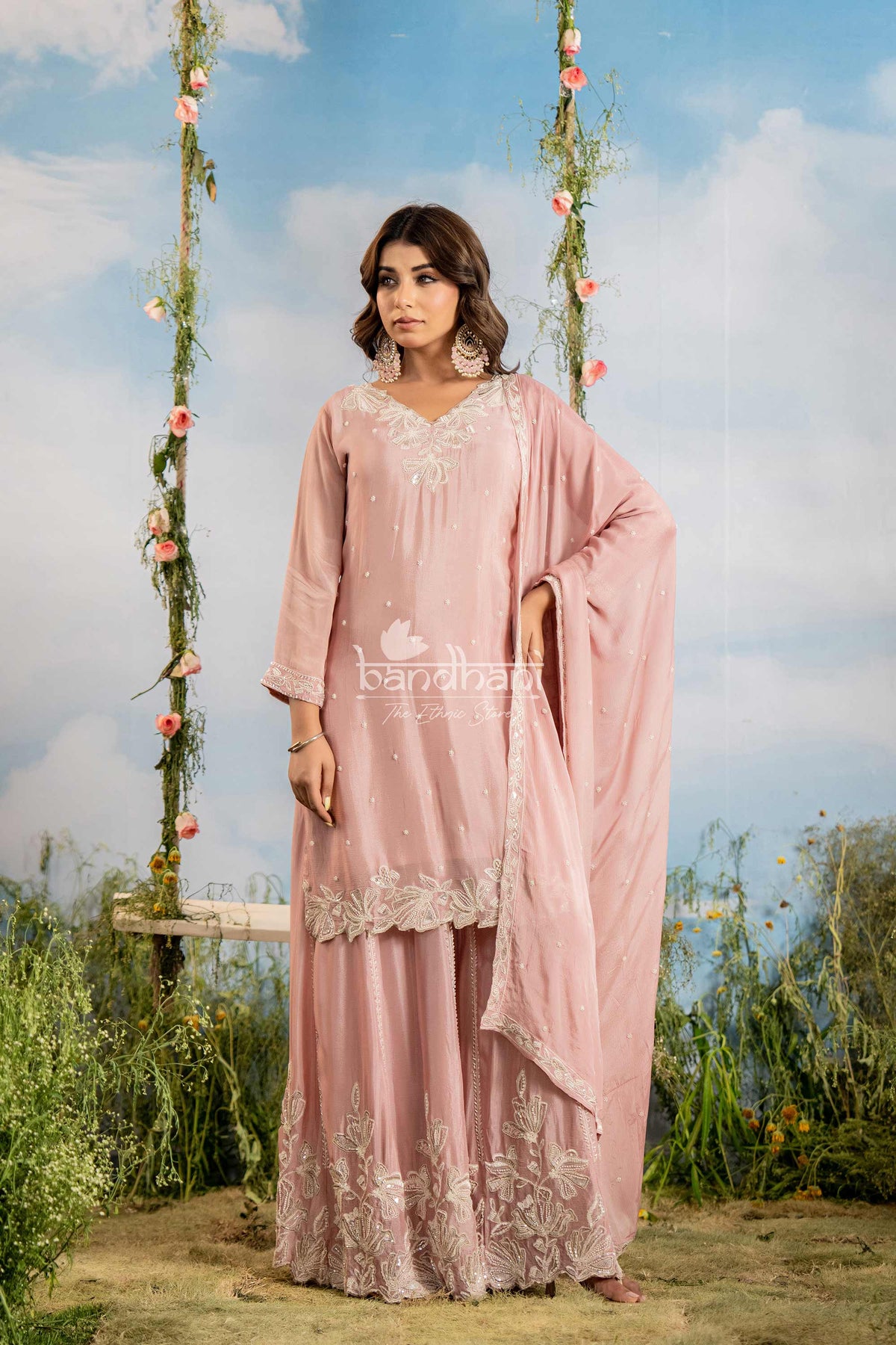 Woman in a pink traditional outfit with floral decorations and 'bandhani' branding.