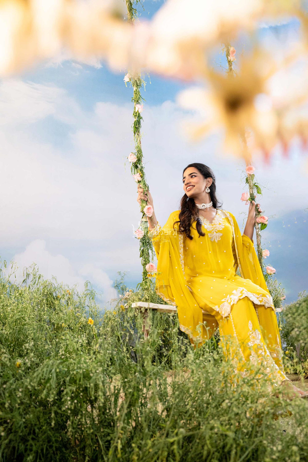 Woman in a yellow traditional outfit sitting on a swing with a scenic background