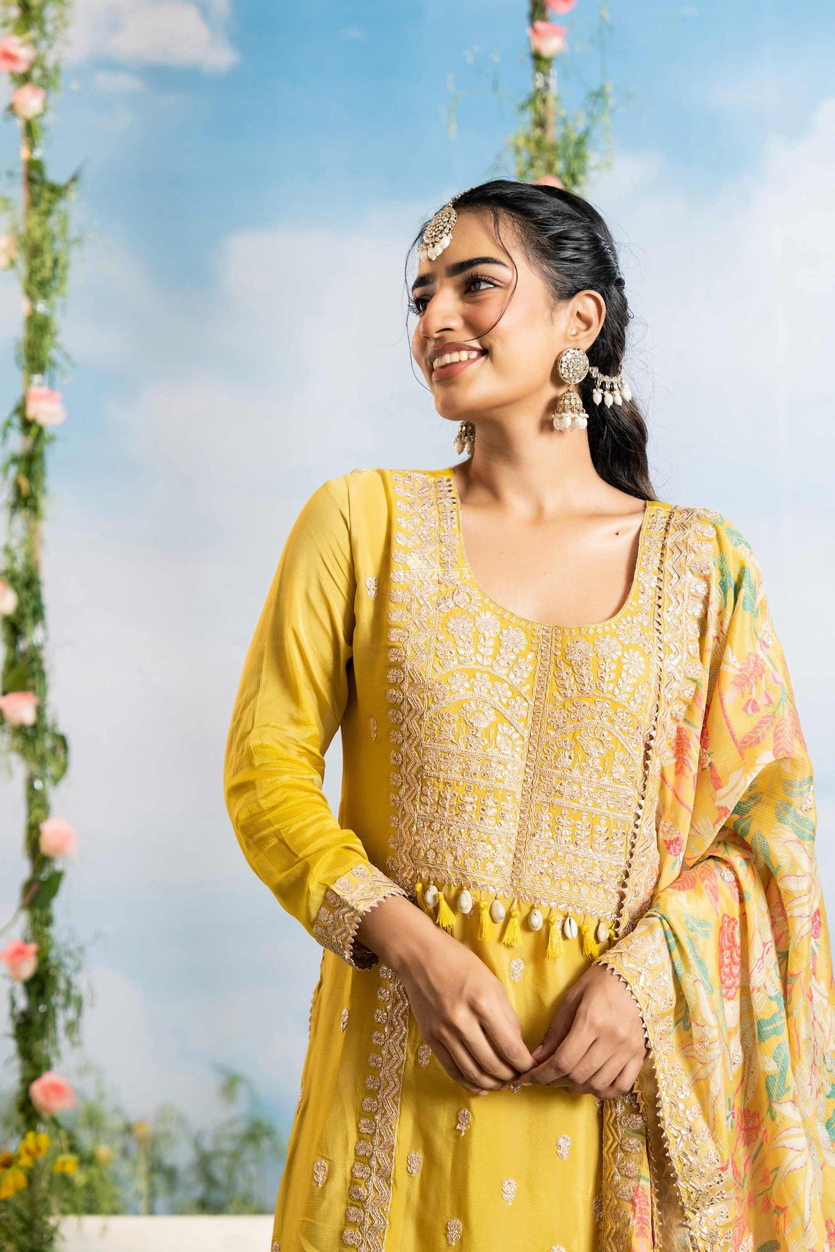 Woman in a yellow traditional outfit with floral decorations in the background