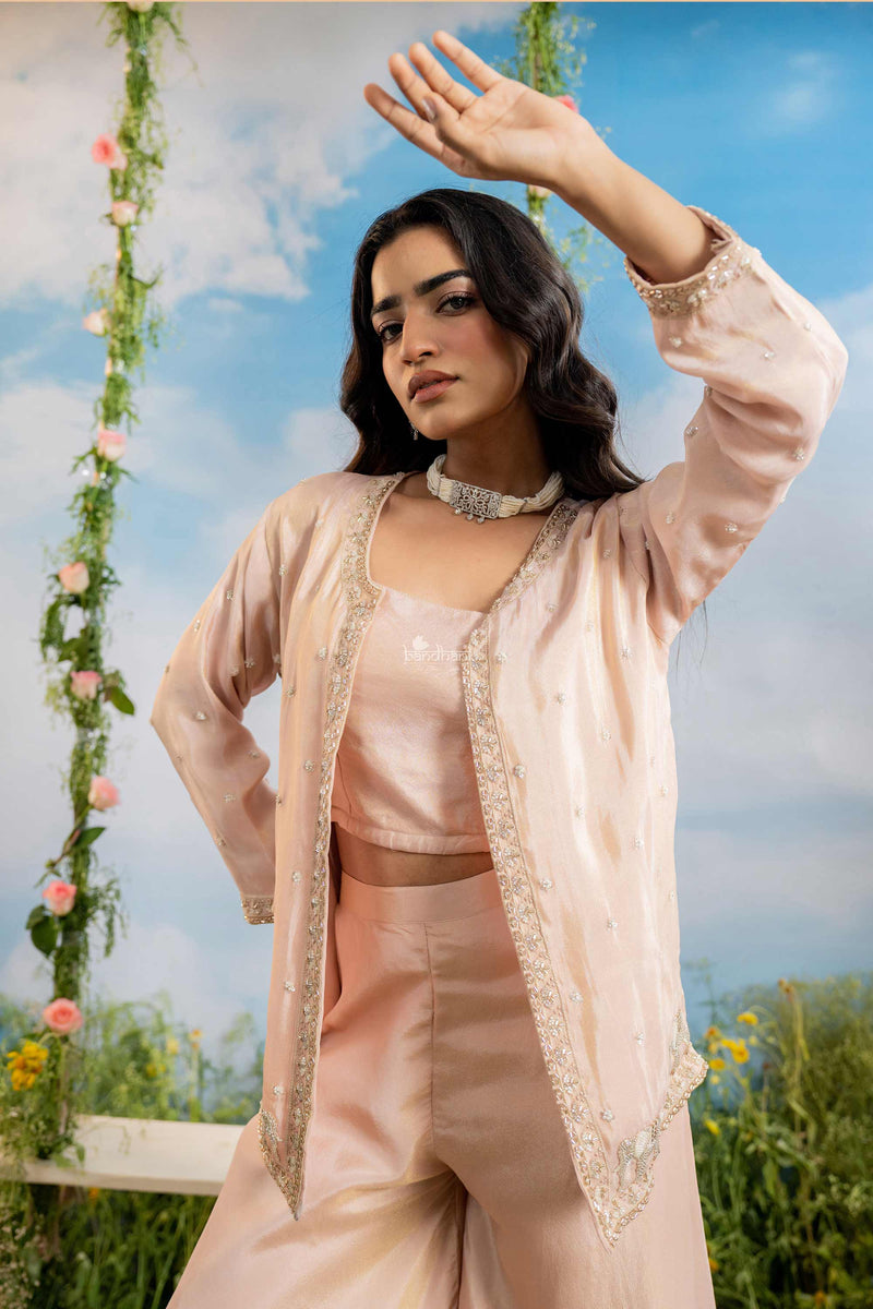 Woman in a peach traditional outfit with floral decorations and a blue sky background