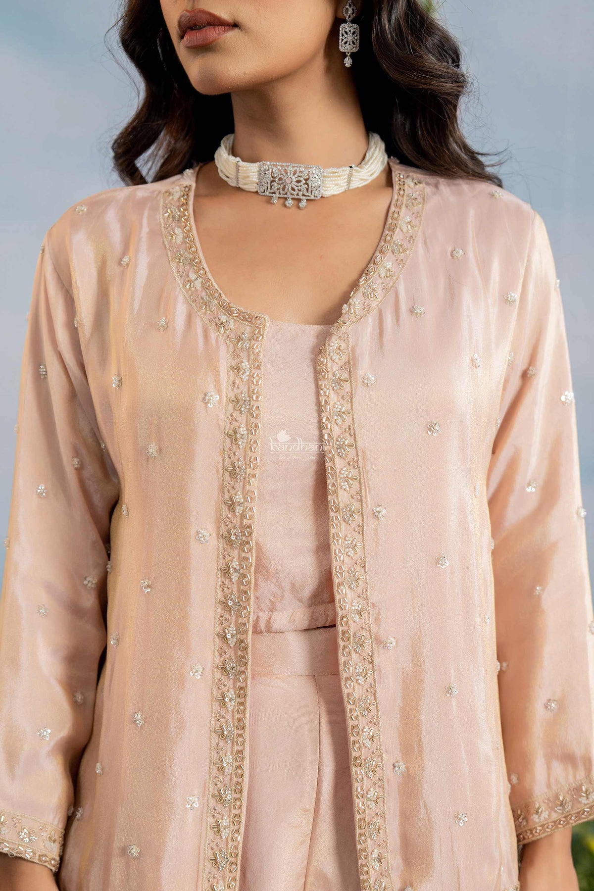 Woman wearing a peach-colored traditional outfit with intricate embroidery.