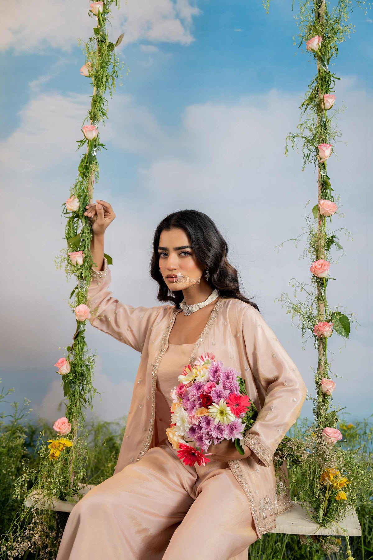 Woman sitting on a floral swing with a blue sky background