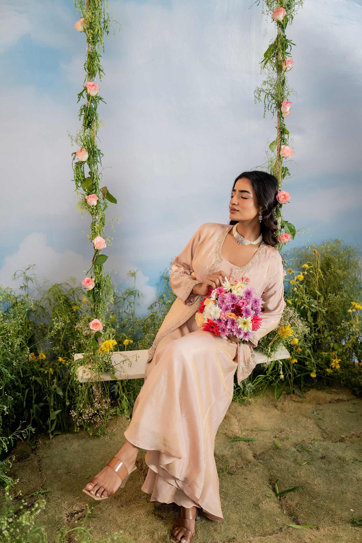 Woman in a flowing dress sitting on a floral swing with a scenic background