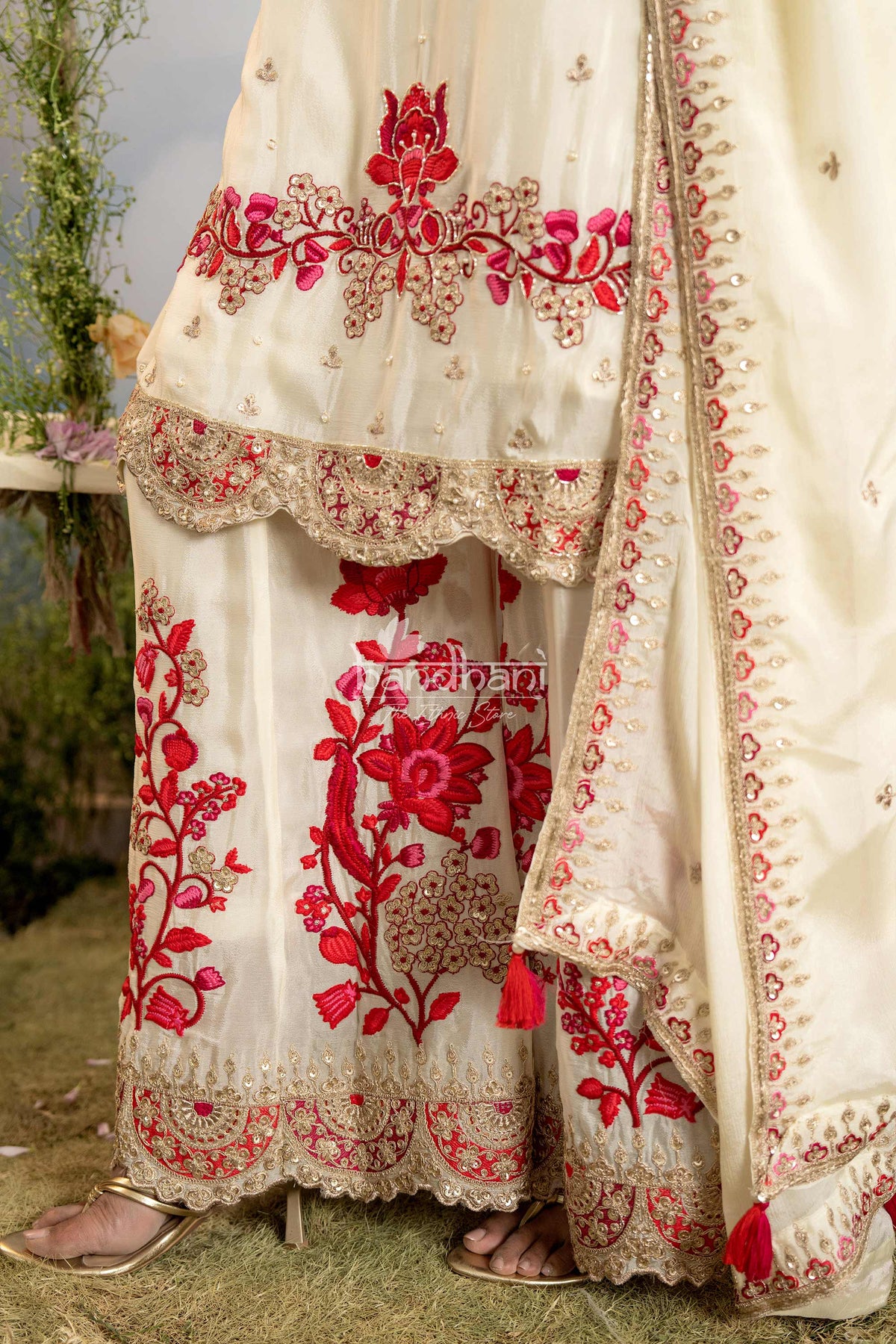 White embroidered outfit with red floral patterns on a grassy background
