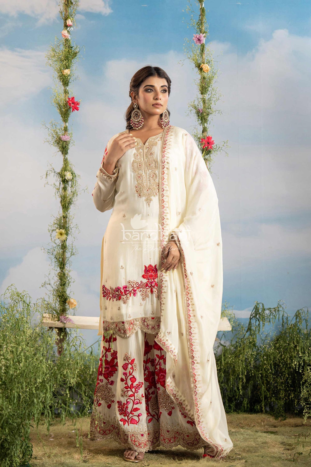 Woman in a traditional outfit with floral patterns standing outdoors against a scenic background.