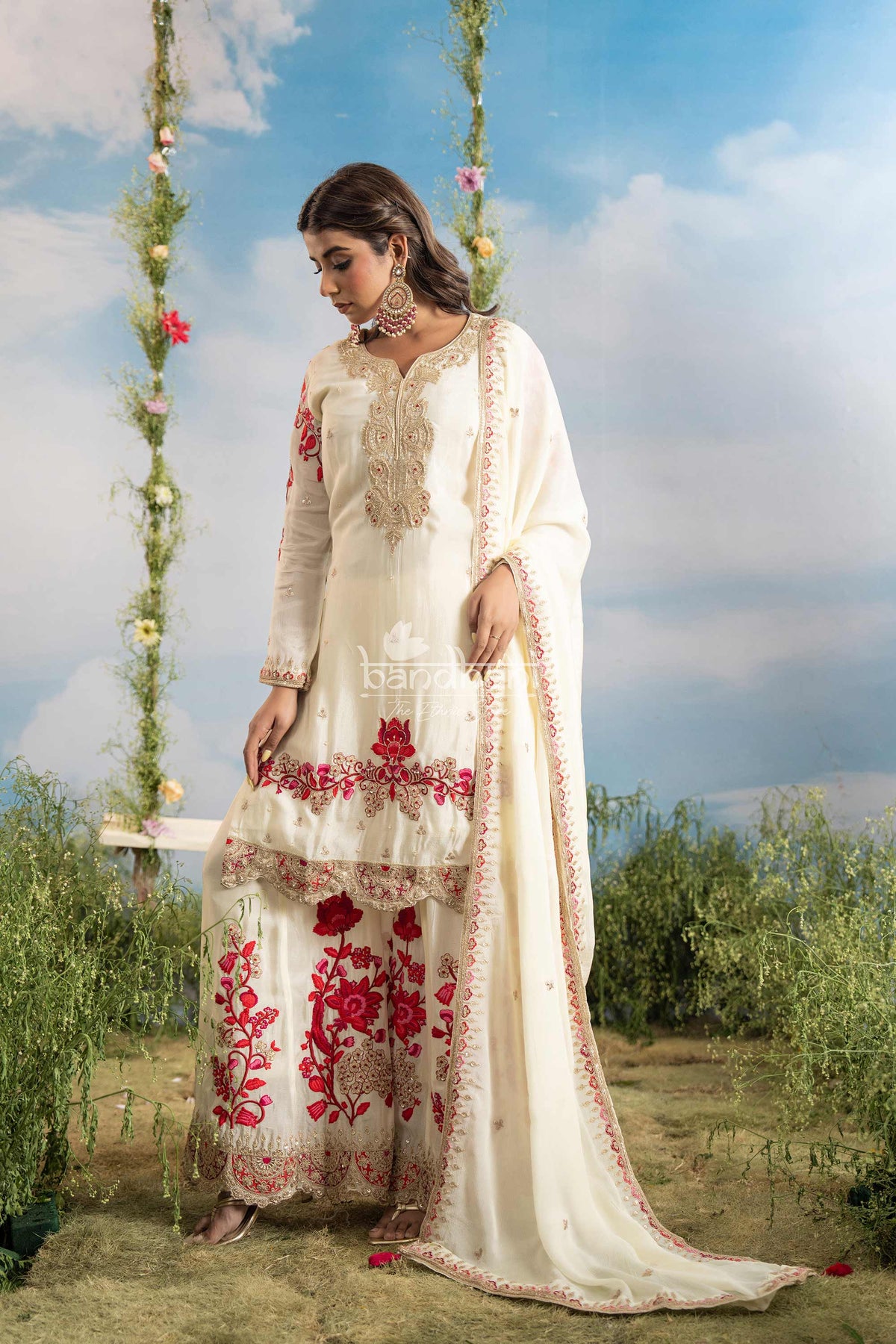 Woman in a white embroidered traditional outfit sitting on a swing with a scenic background