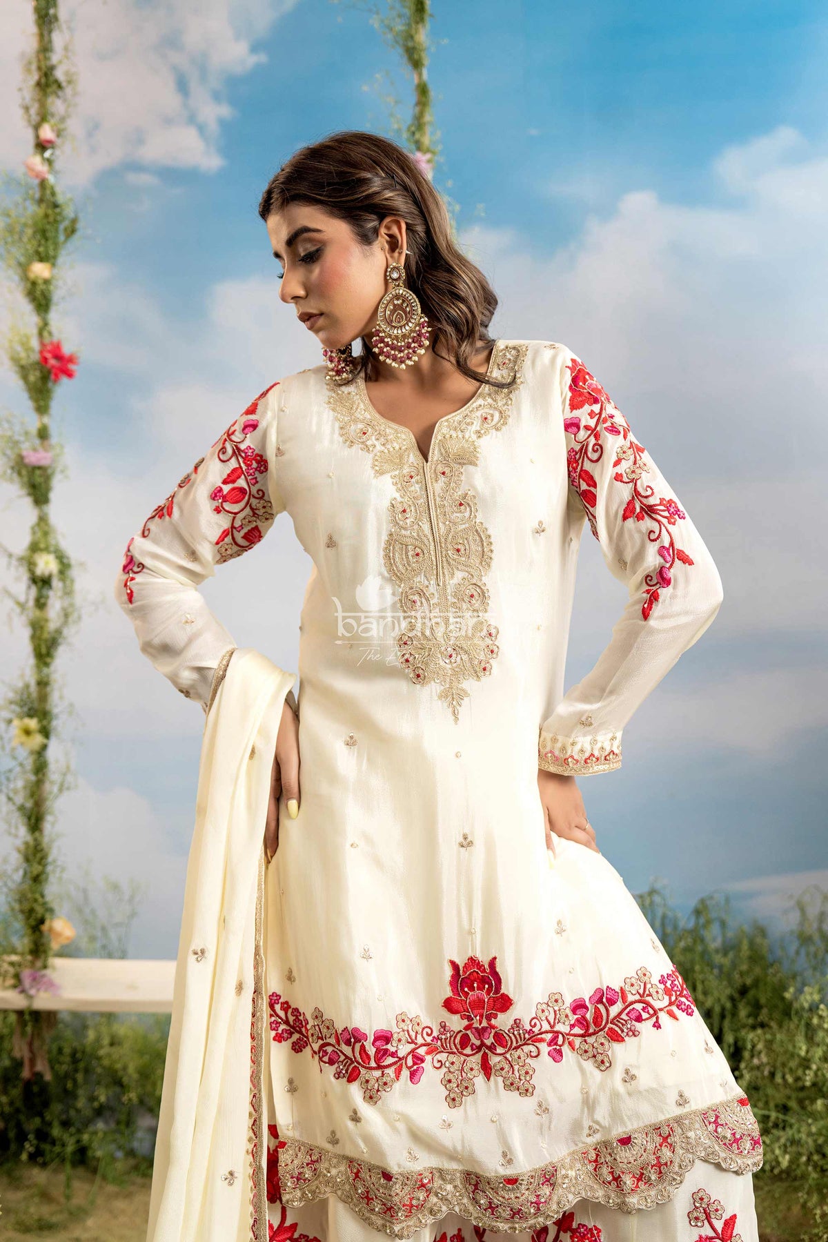 Woman wearing a white embroidered traditional outfit with red details against a natural background.