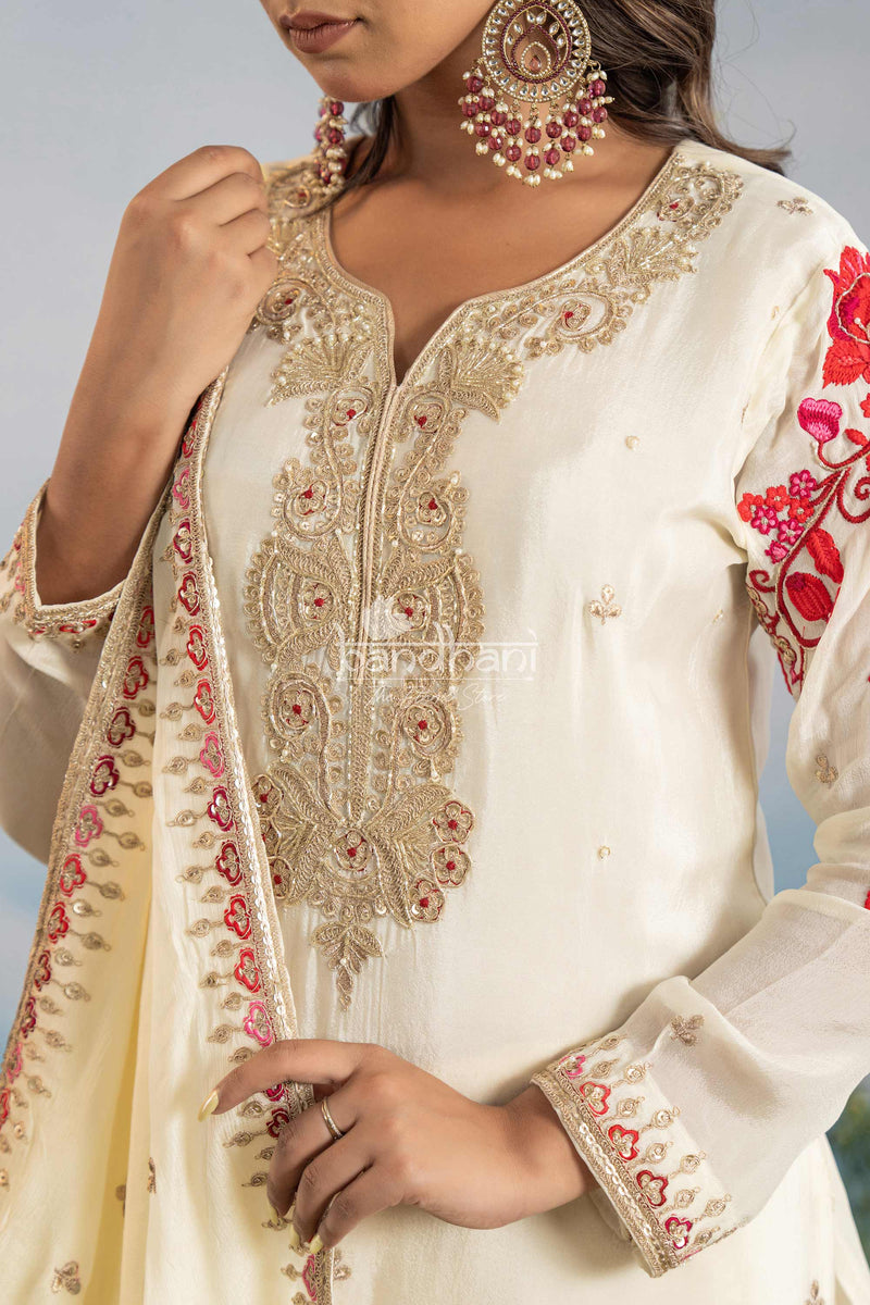 White embroidered outfit with red floral patterns on a neutral background