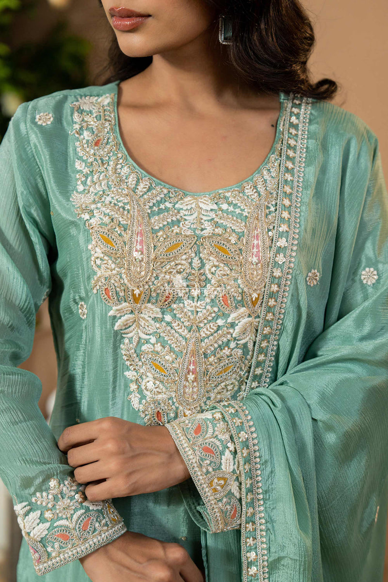 Close-up of a teal embroidered traditional outfit with intricate patterns.