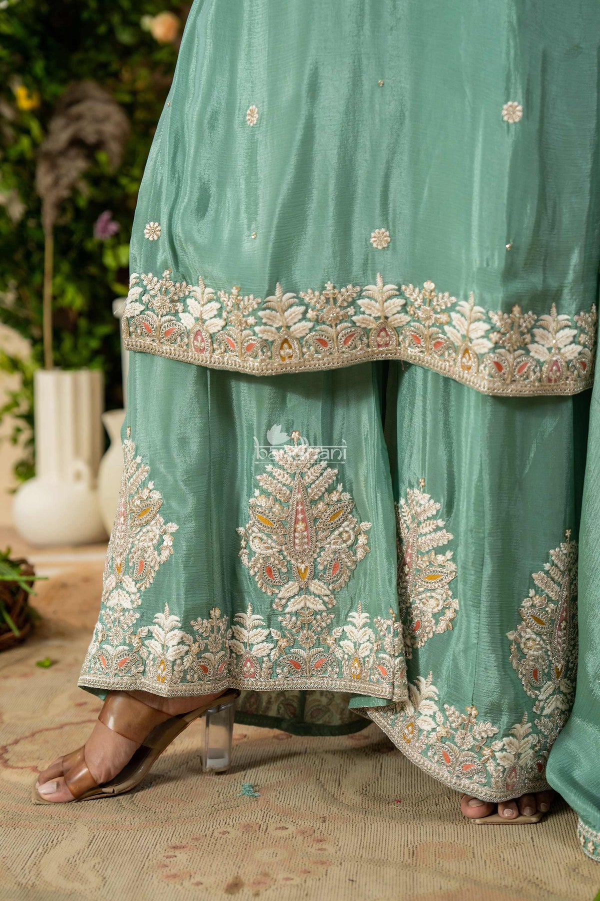 Teal traditional outfit with intricate embroidery on a blurred natural background