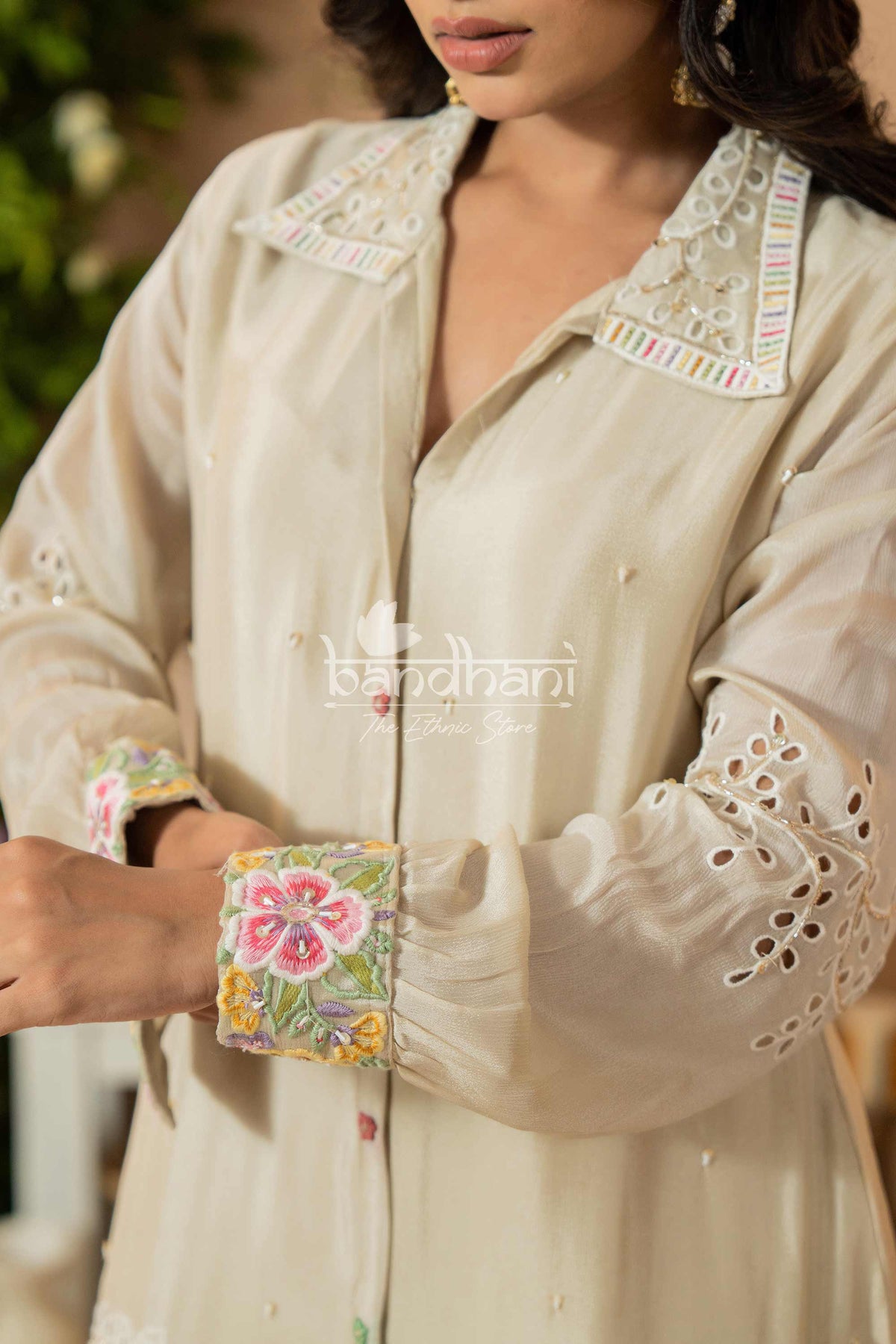 Beige embroidered traditional outfit with floral cuffs and collar, brand 'Bodhini' visible.