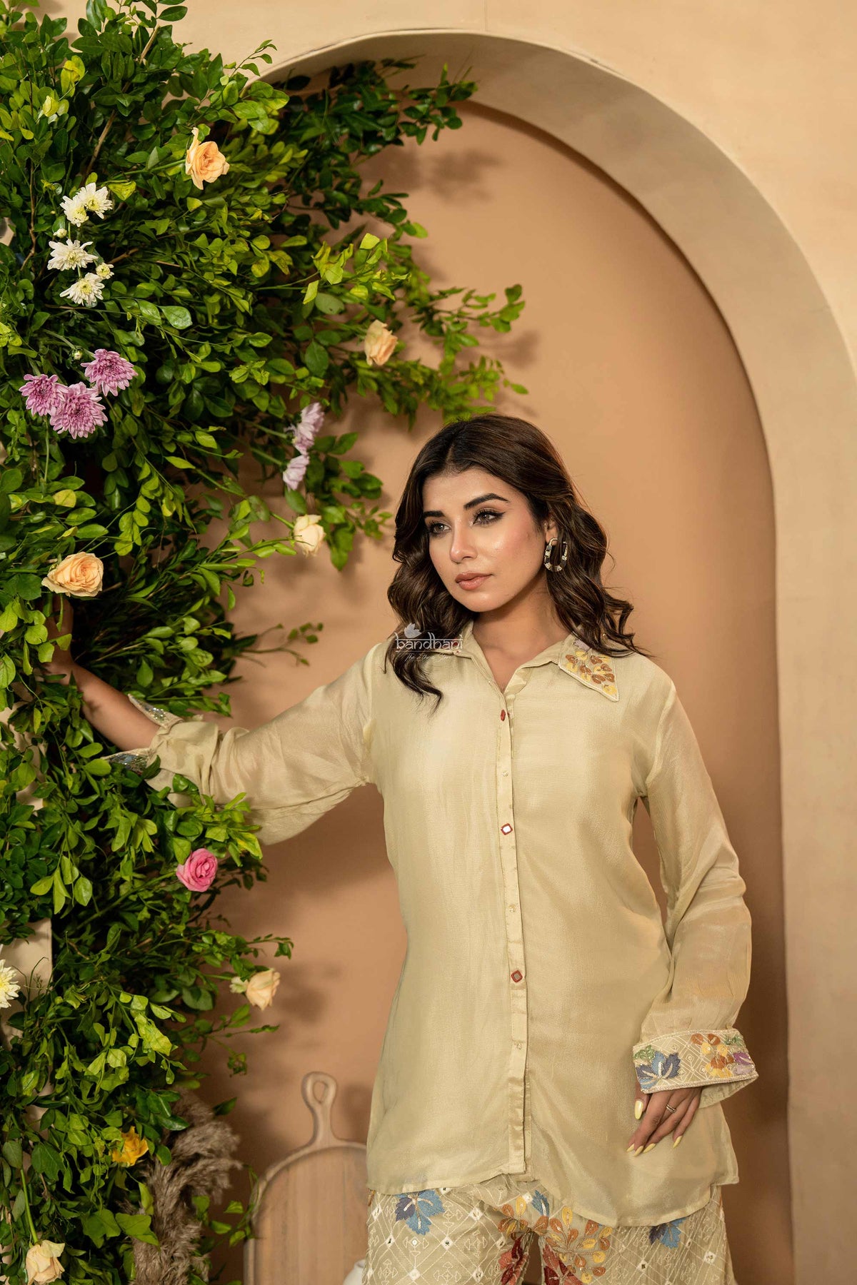 Woman in a light-colored outfit standing next to floral decorations