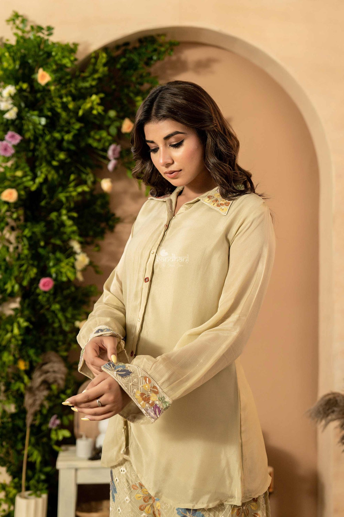 Woman wearing a beige embroidered shirt in a decorated indoor setting