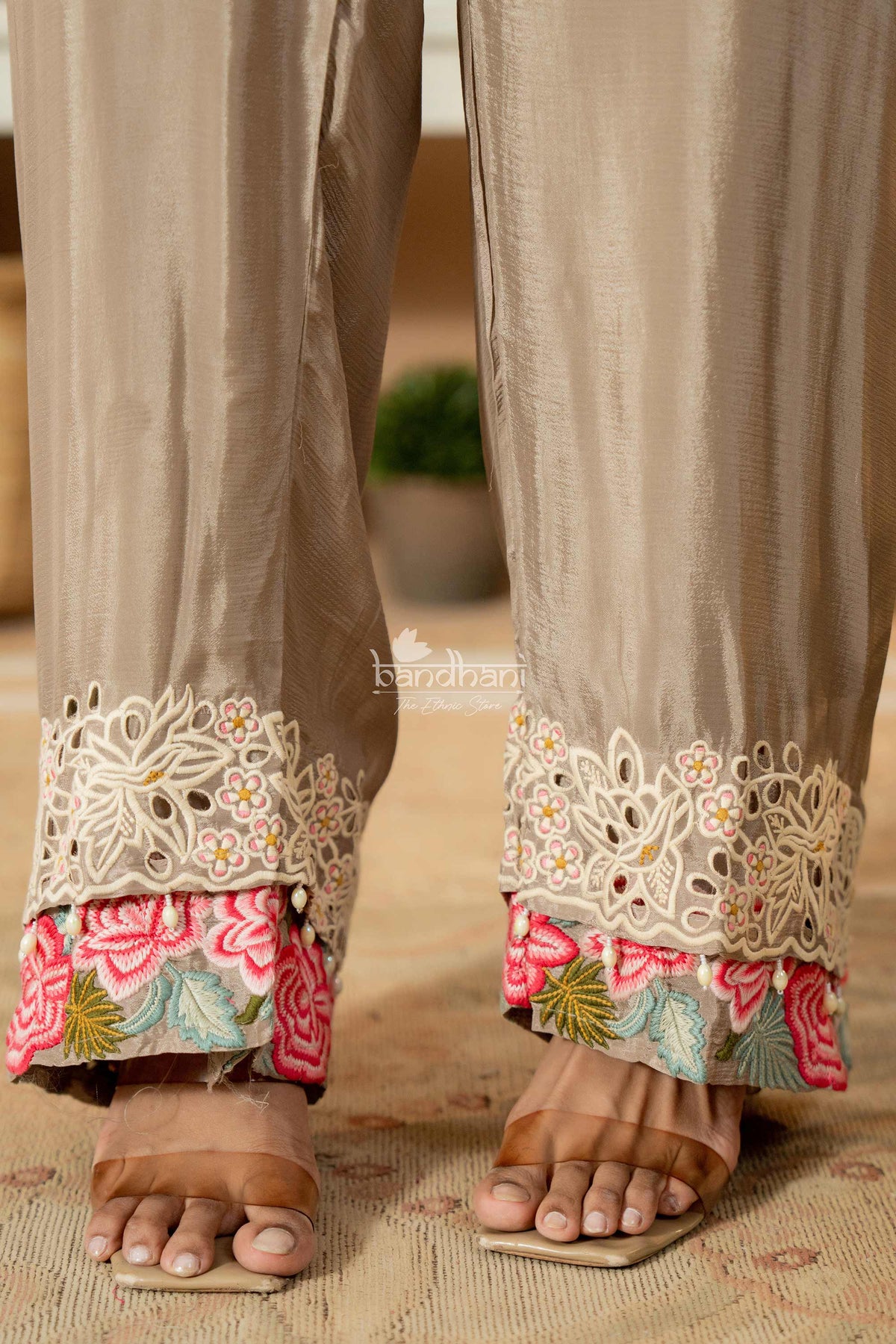 Beige pants with floral and lace embroidery at the bottom worn by a person.