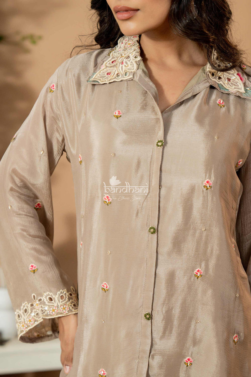 Light brown embroidered shirt with floral patterns on a neutral background