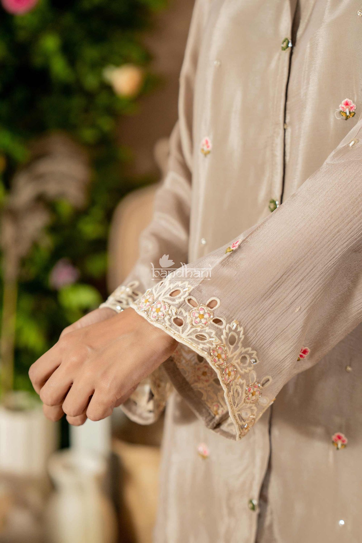 Close-up of a person wearing a beige embroidered garment with a blurred background