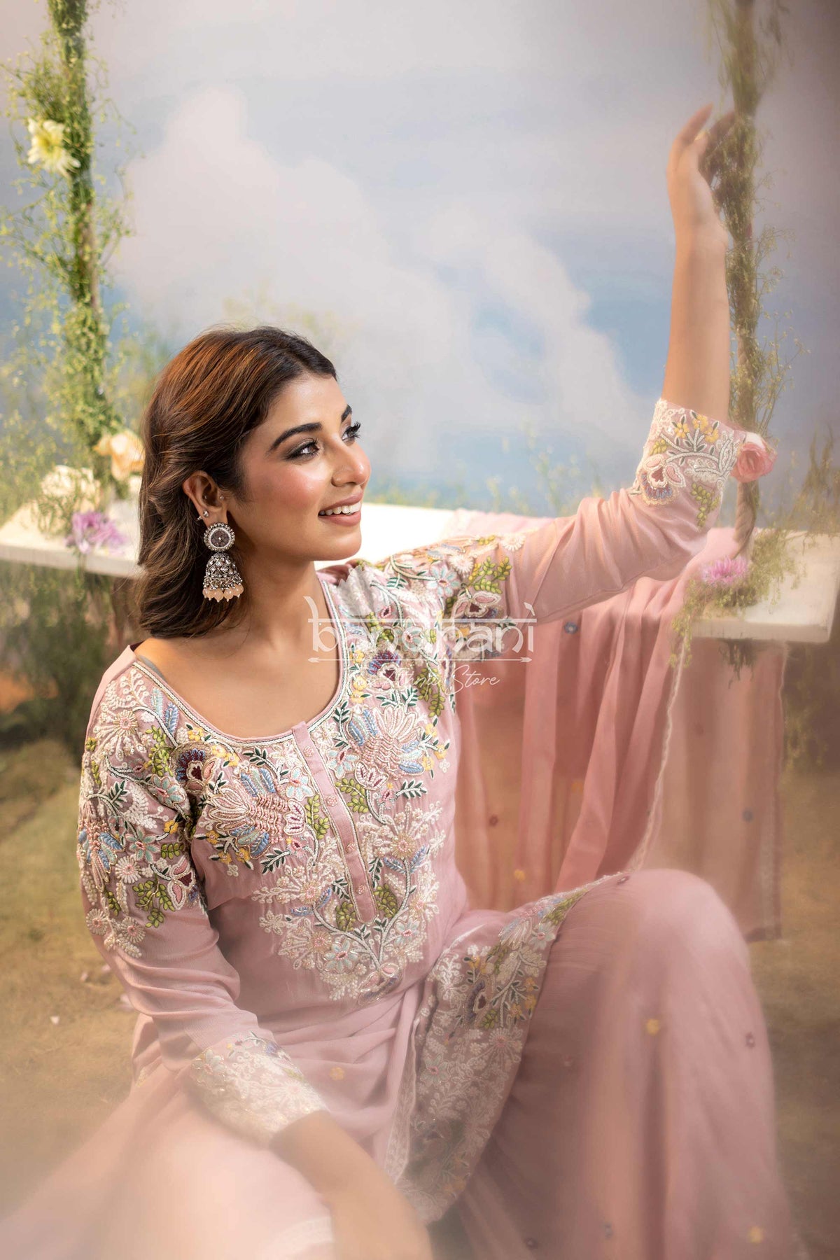 Woman in a pink embroidered outfit sitting outdoors with a blurred background