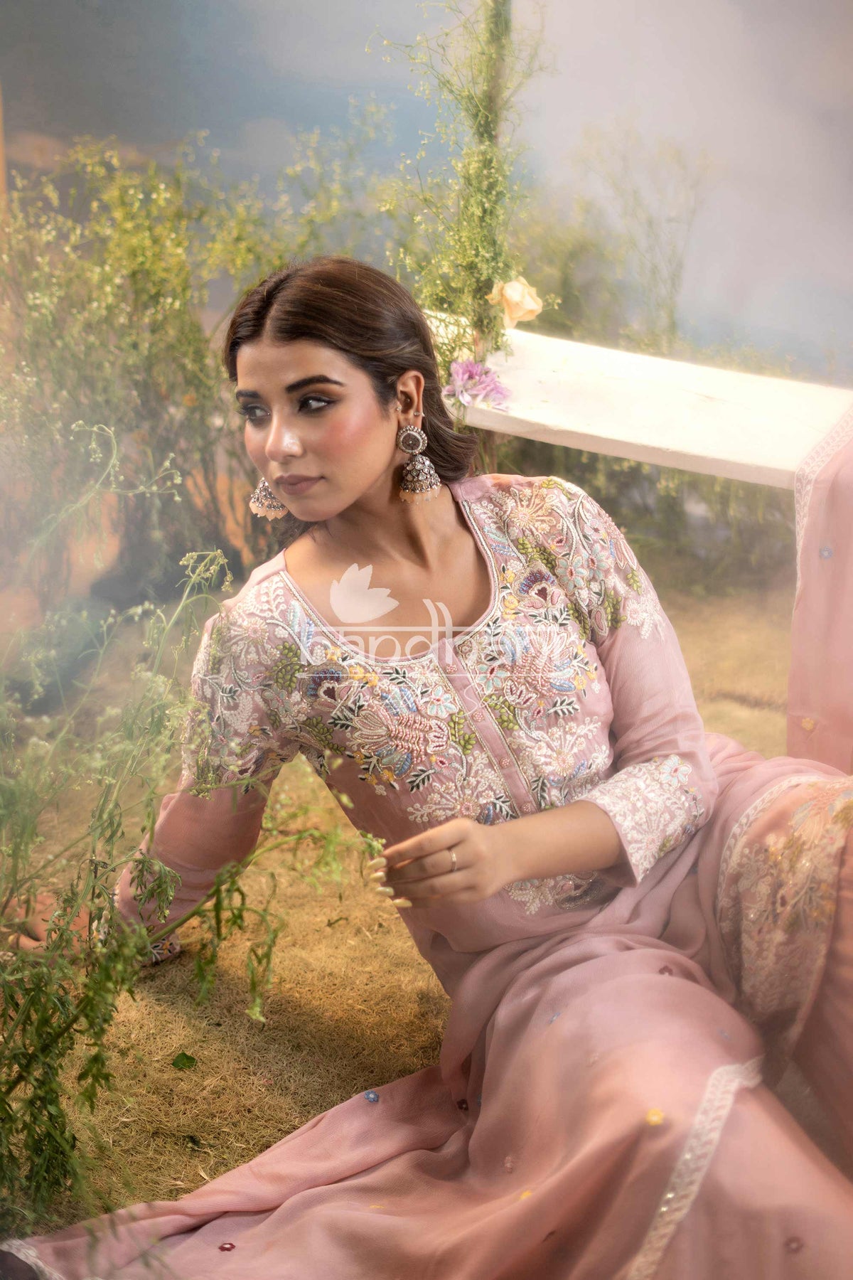 Woman in a floral outfit sitting outdoors with greenery in the background