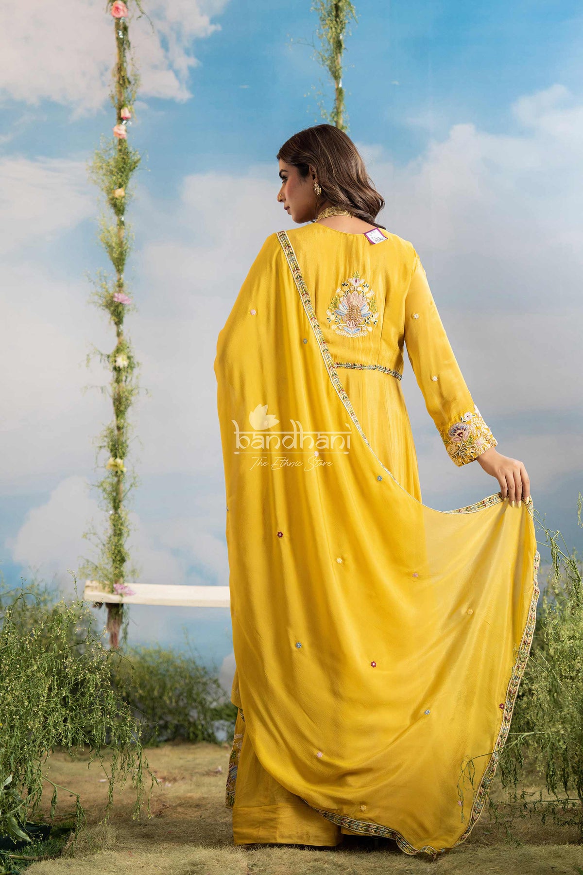 Woman in a yellow traditional outfit with floral decorations against a blue sky.