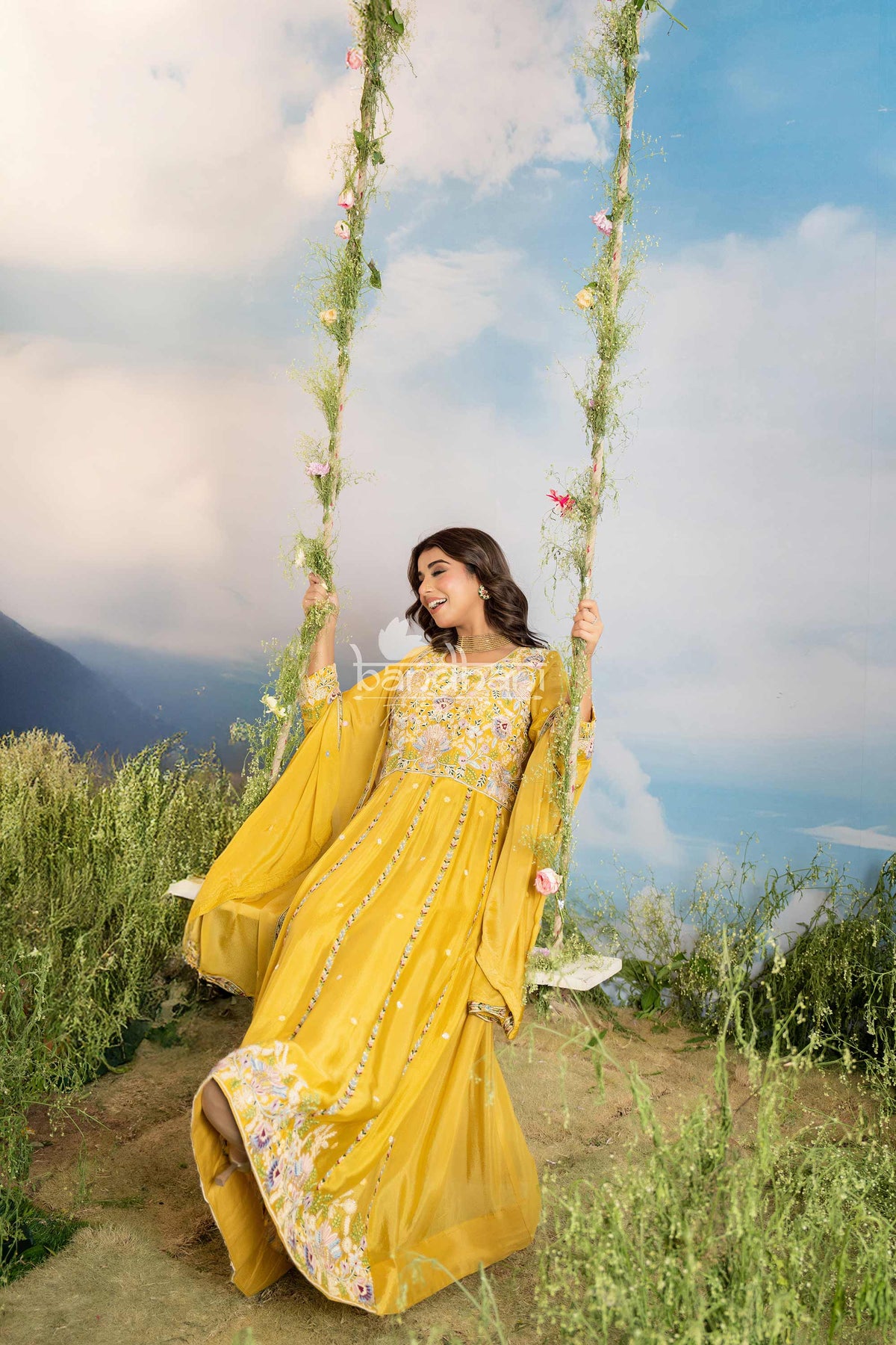 Woman in a yellow traditional outfit sitting on a swing with a scenic background