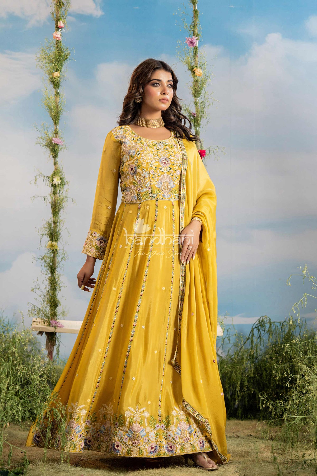Woman in a yellow traditional outfit with floral patterns against a scenic background