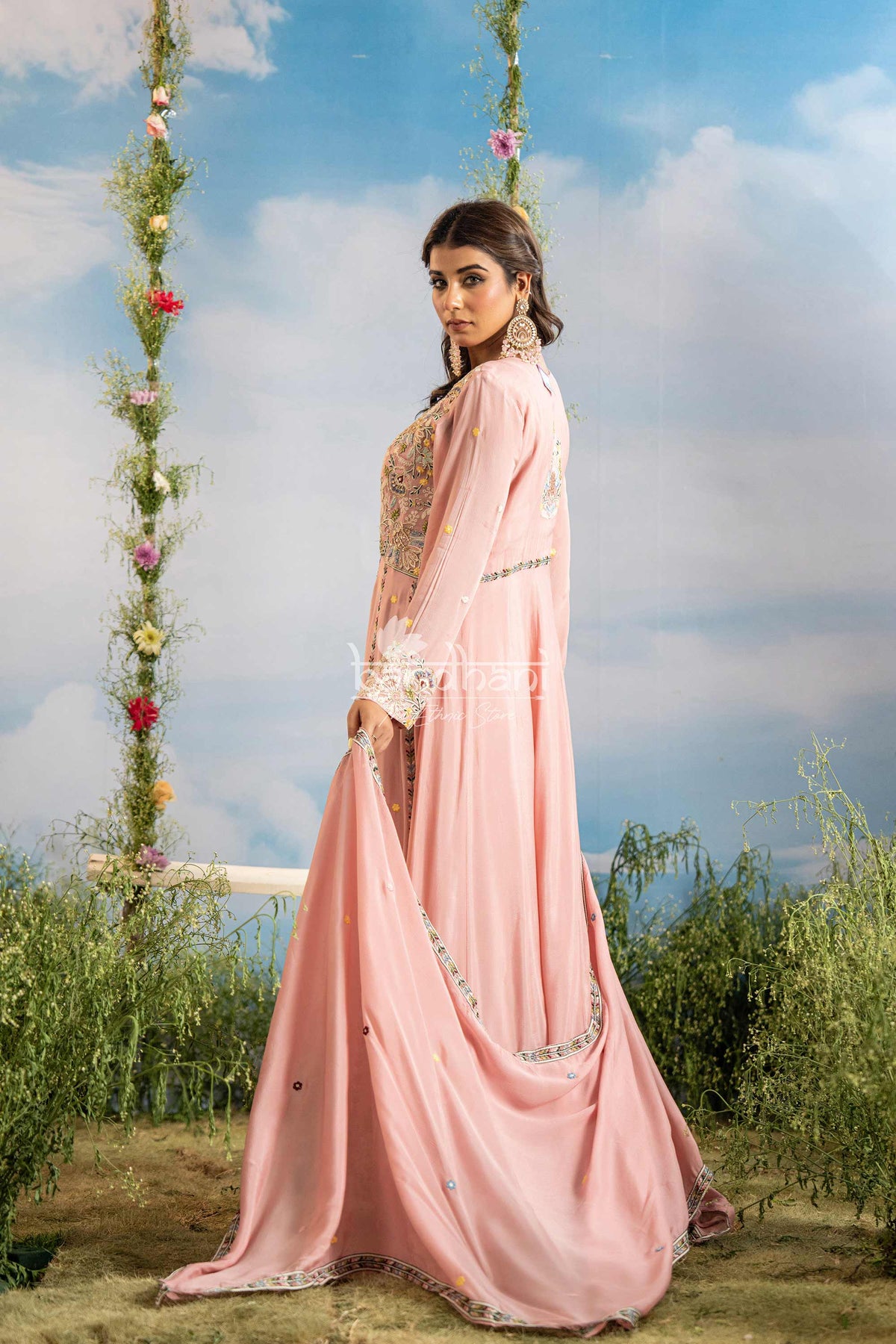 Woman in a pink traditional outfit standing outdoors with decorative elements.