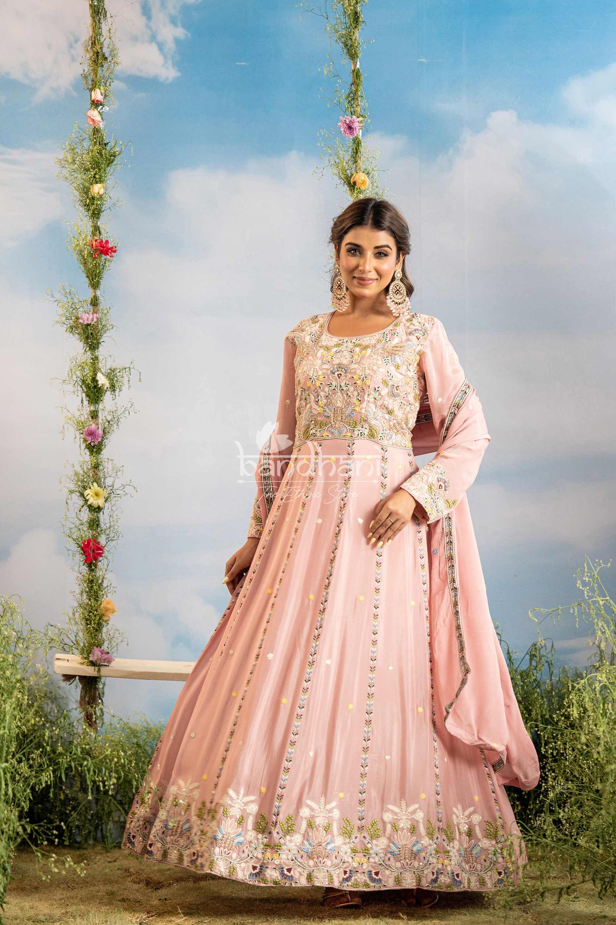Woman in a pink traditional outfit with floral decorations against a blue sky.