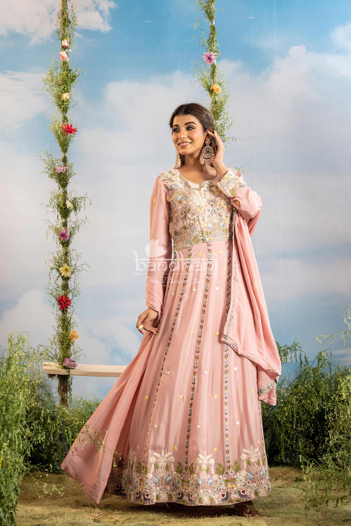 Woman in a pink traditional outfit with floral patterns against a natural background