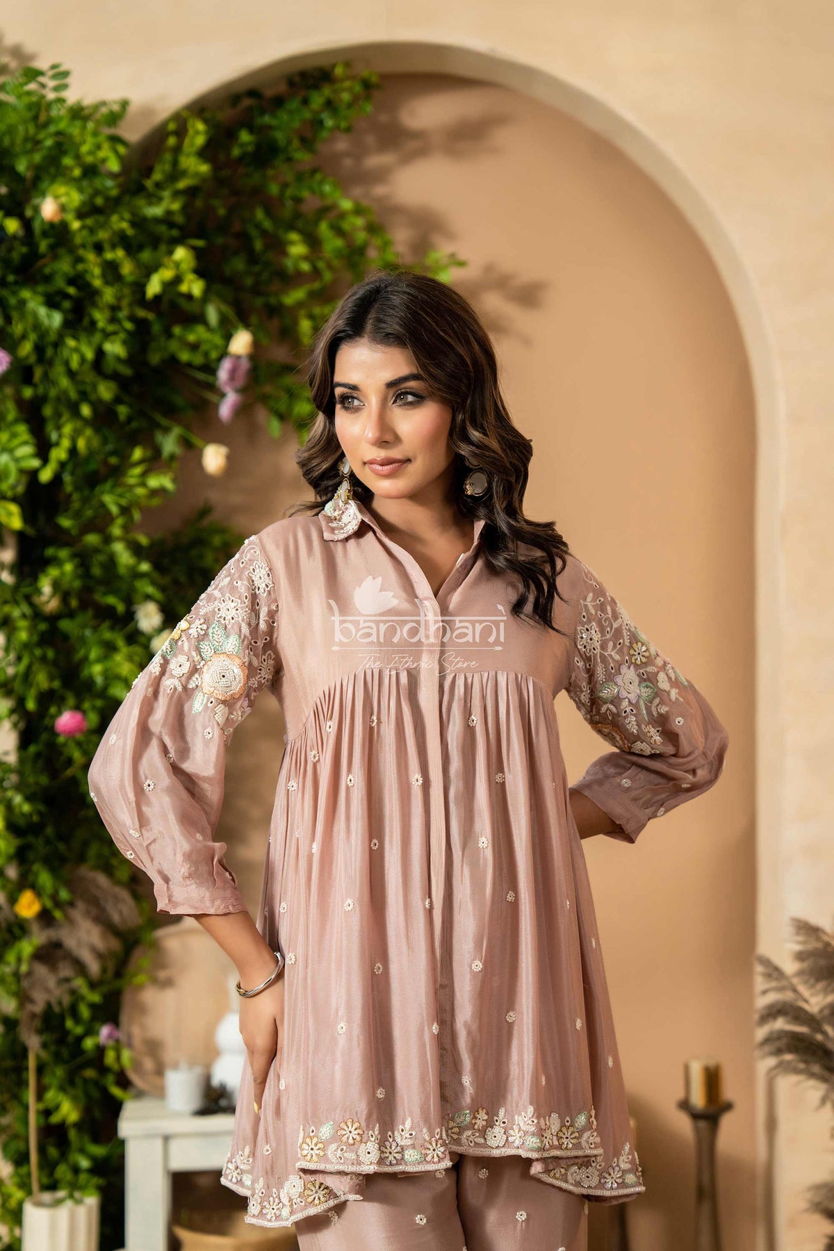 Woman wearing a pink embroidered outfit with a decorative background