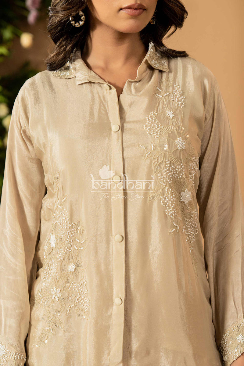 Beige embroidered shirt with 'bandhani' branding on a blurred background