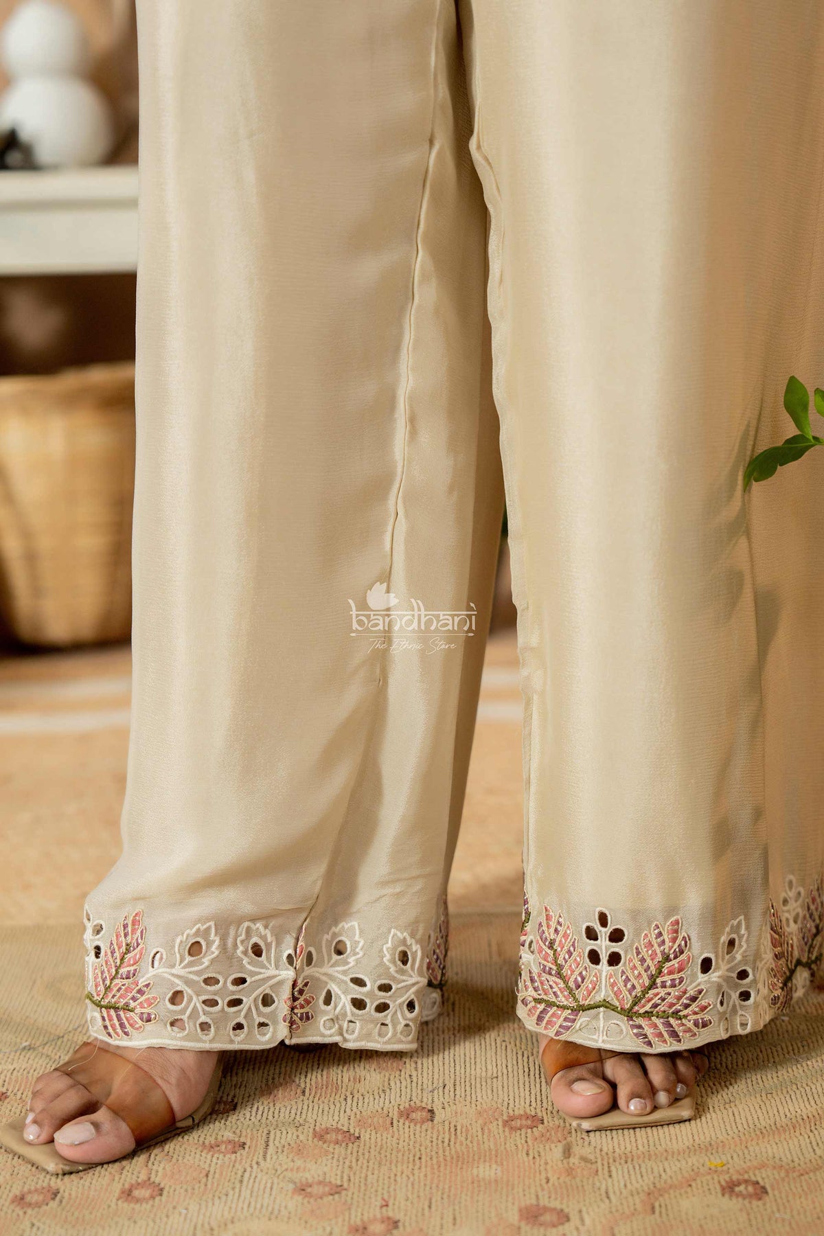Beige pants with floral embroidery at the bottom worn by a person indoors.