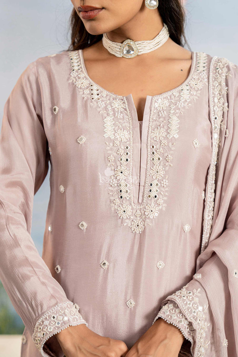 Close-up of a light pink traditional outfit with intricate white embroidery.