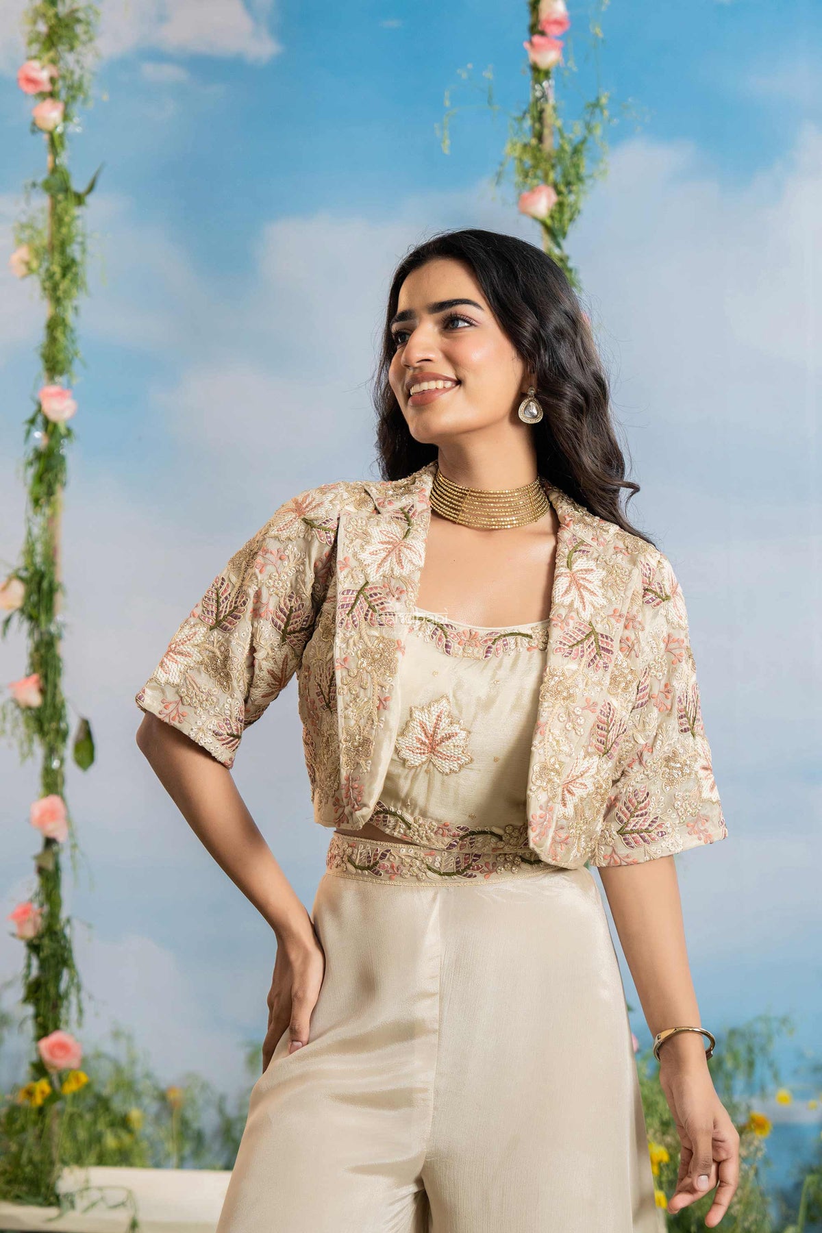 Woman wearing a floral blouse and beige pants against a blue sky with flowers.