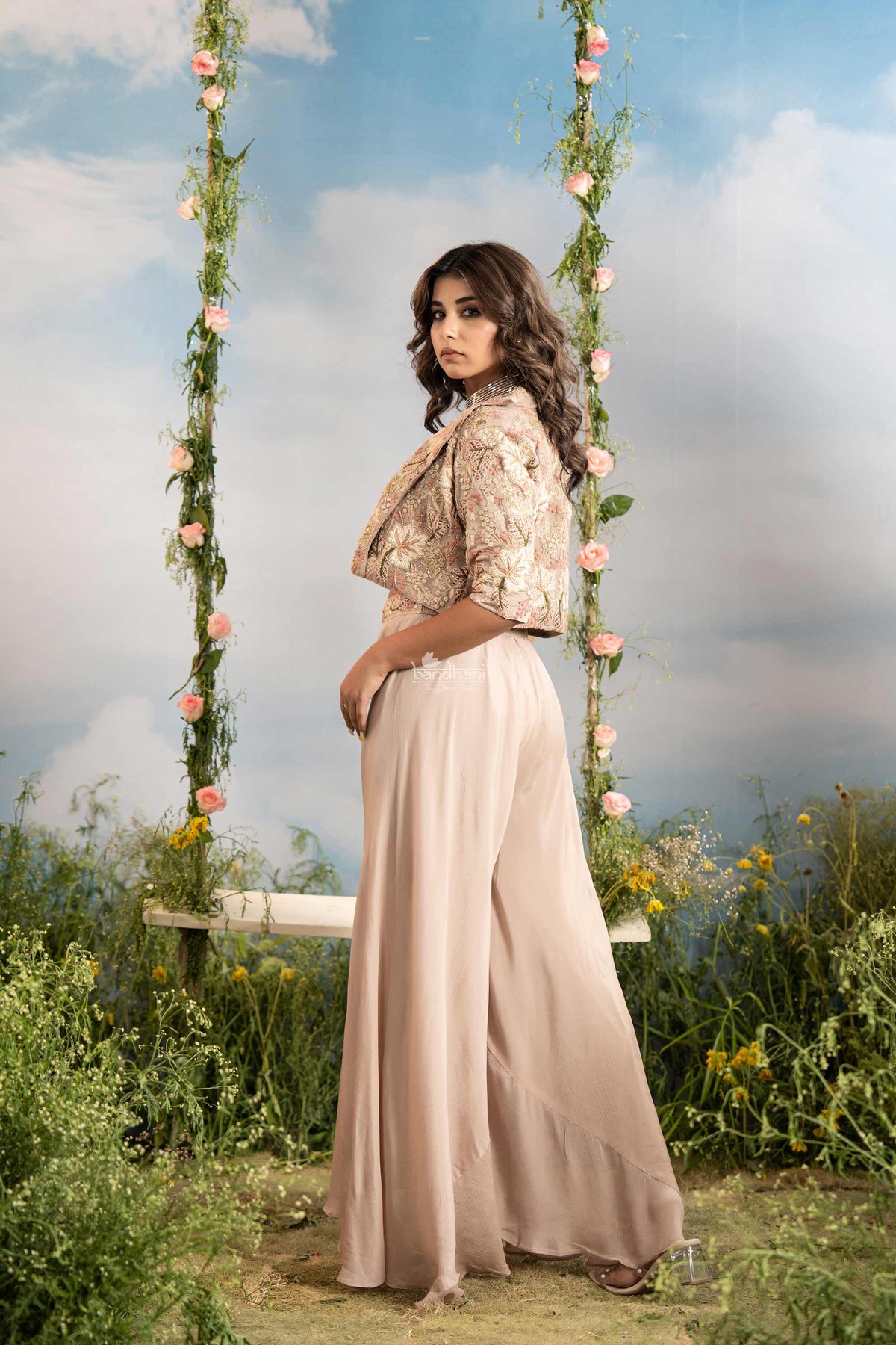 Woman in a beige outfit sitting on a floral swing with a natural background