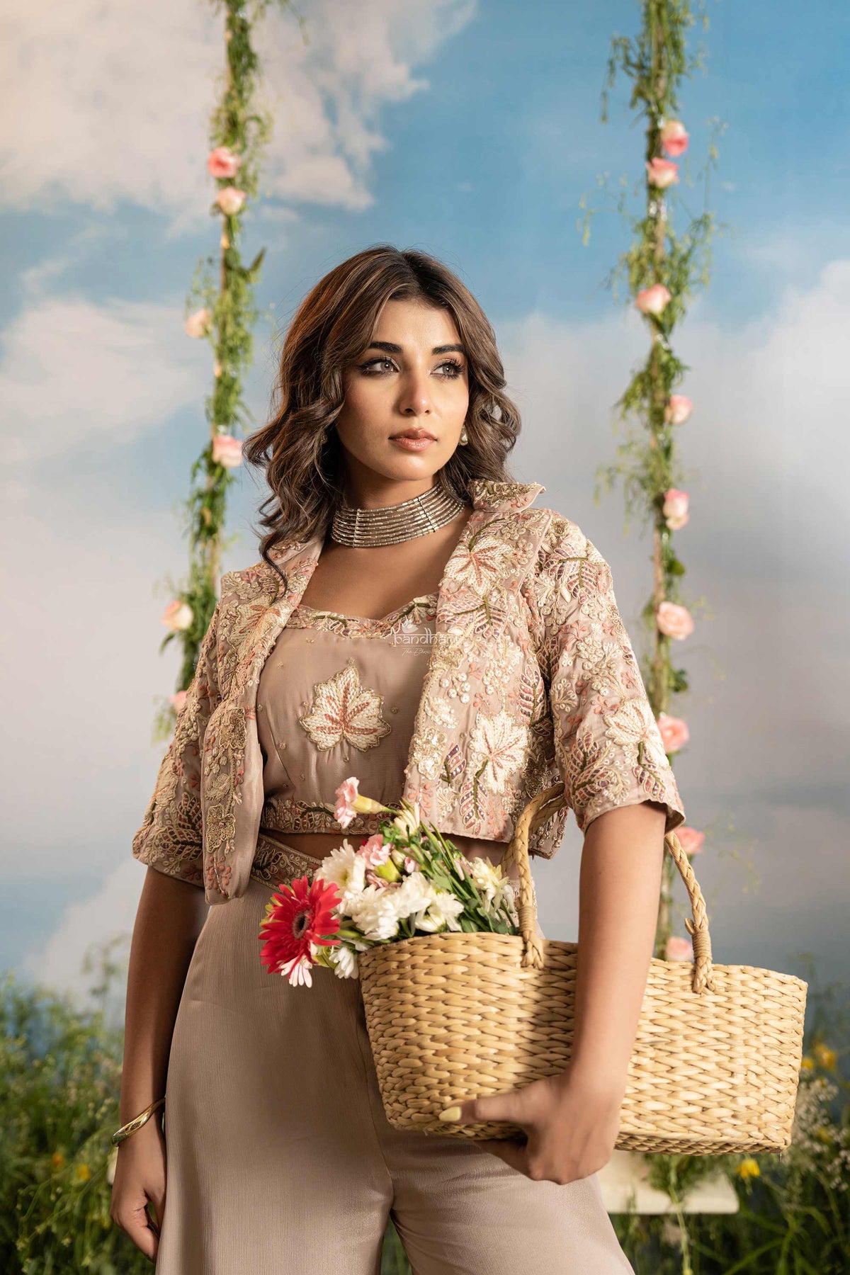 Woman holding a basket of flowers with a floral swing and blue sky in the background