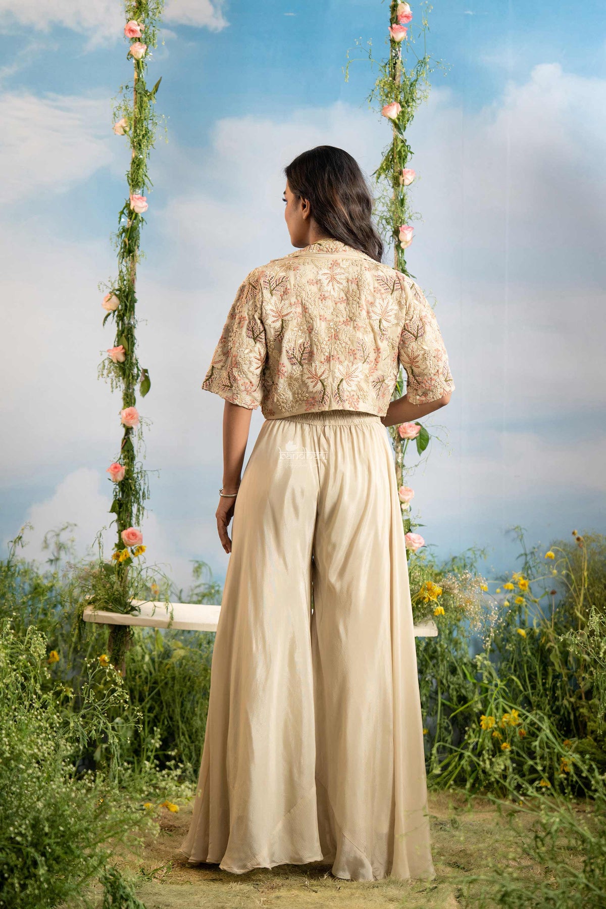 Woman in a beige outfit sitting on a floral swing with a scenic background