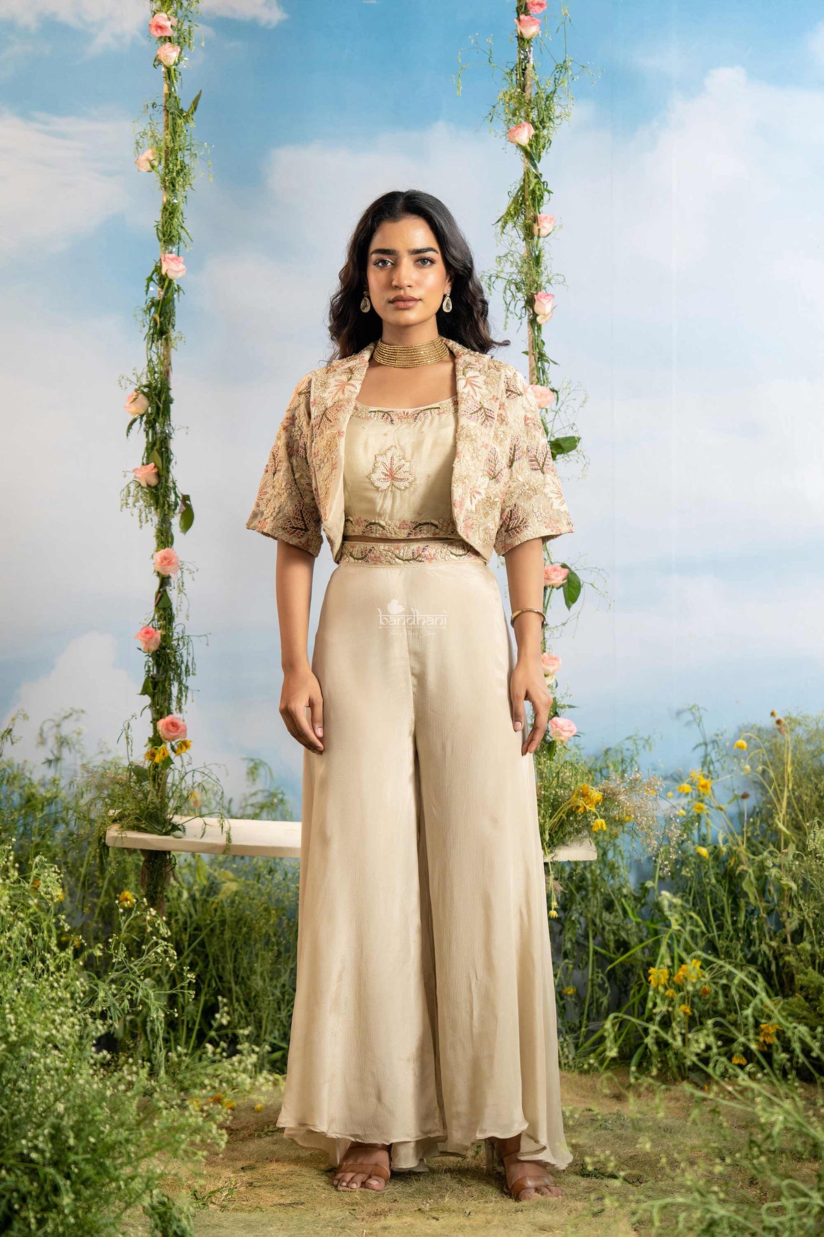 Woman in a beige outfit standing in a garden with floral swing