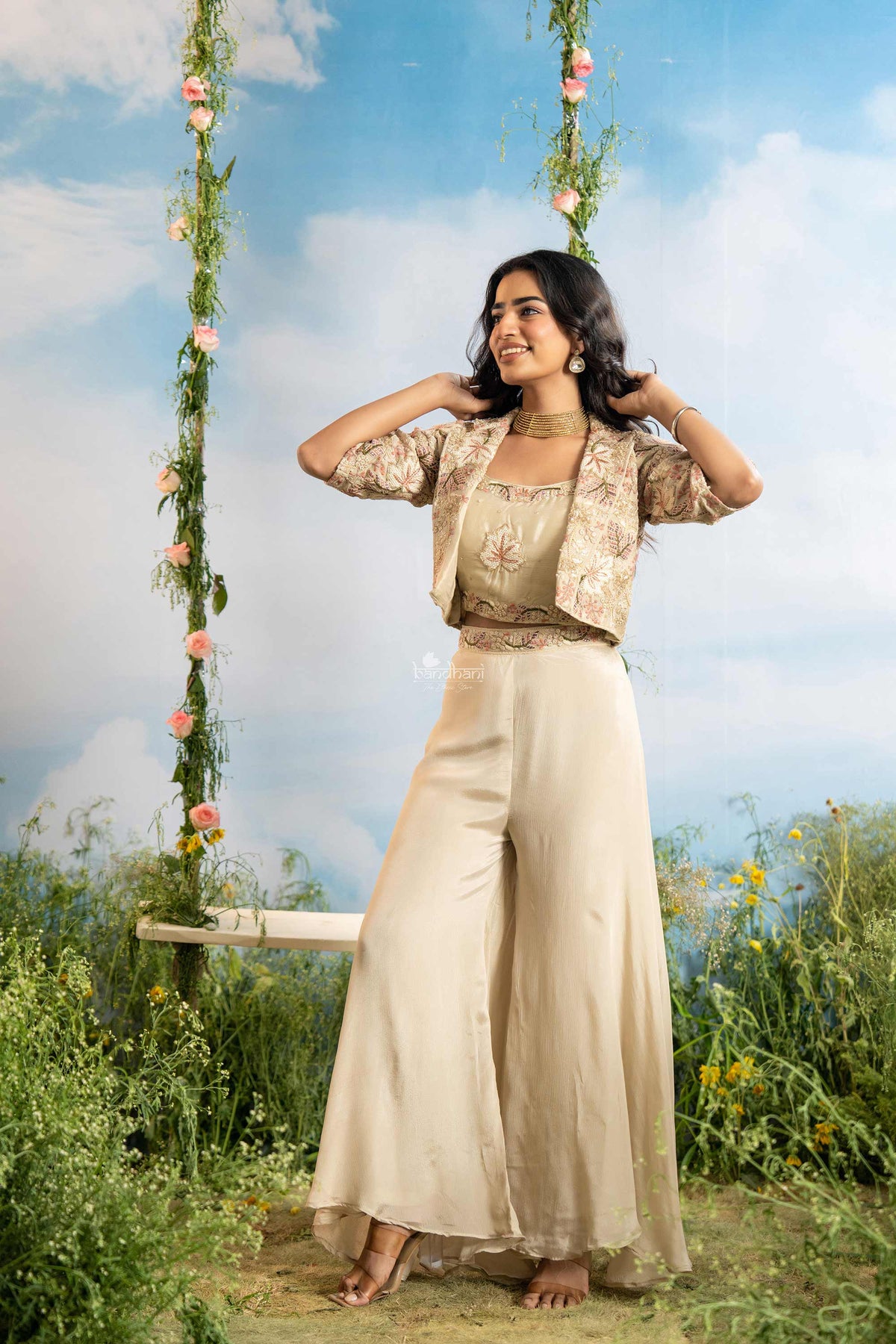 Woman in a traditional outfit standing on a grassy field with a floral swing in the background