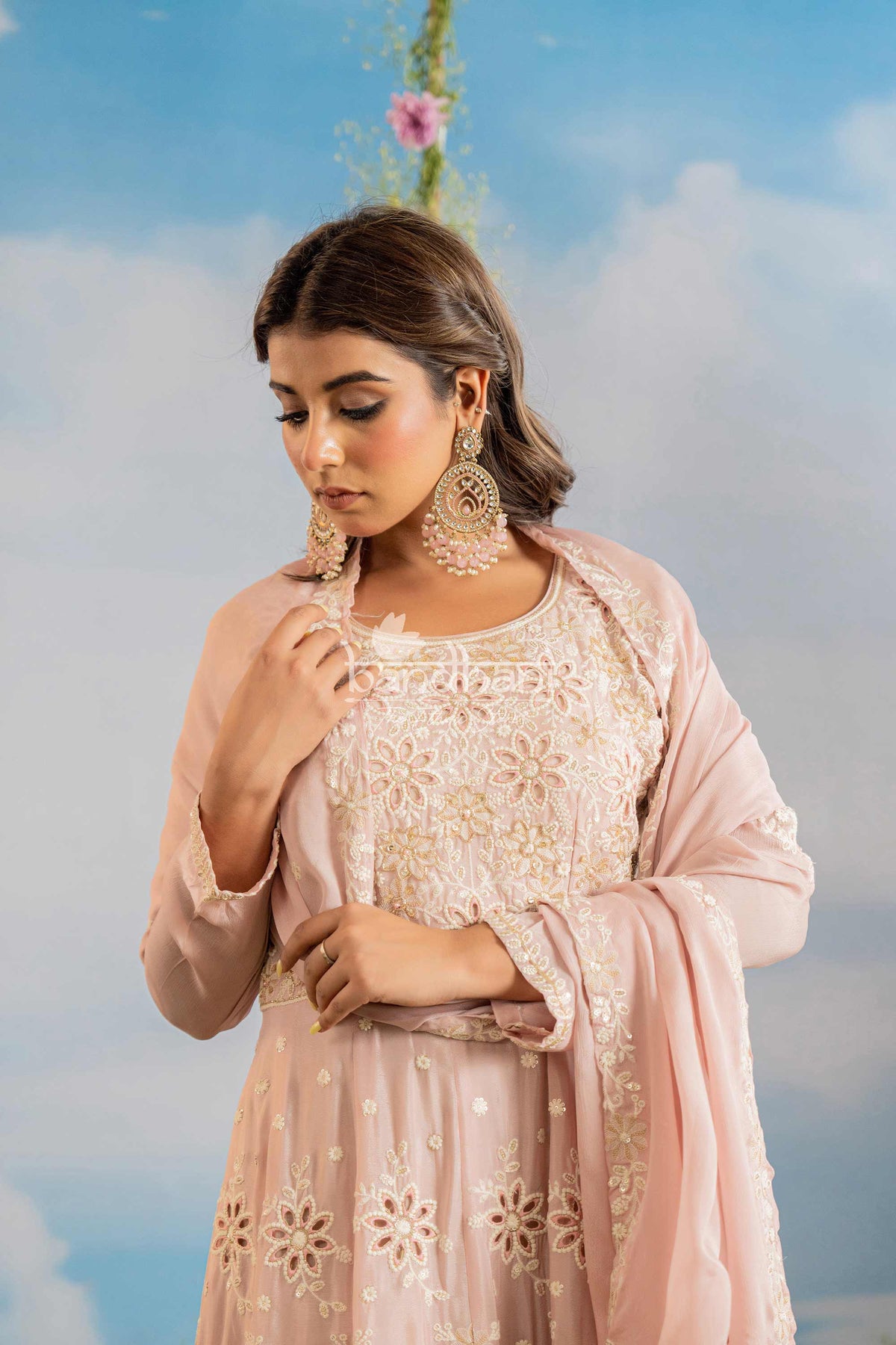 Woman in a pink traditional outfit with floral patterns against a blue sky.